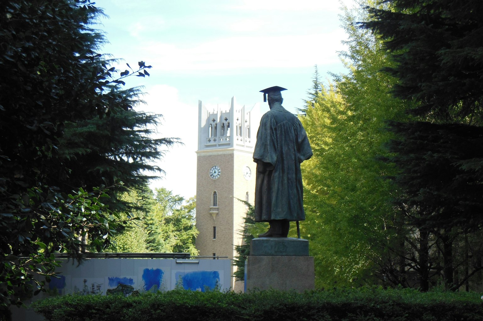 Statue eines Absolventen mit einem Turm im Hintergrund