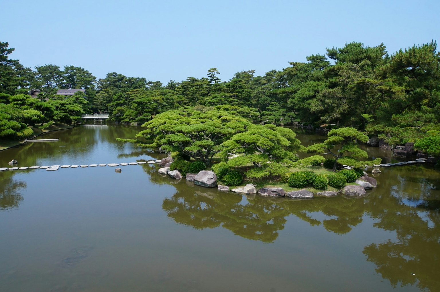 ทิวทัศน์งดงามของสวนญี่ปุ่นที่มีสระน้ำสงบและพืชพรรณเขียวขจี