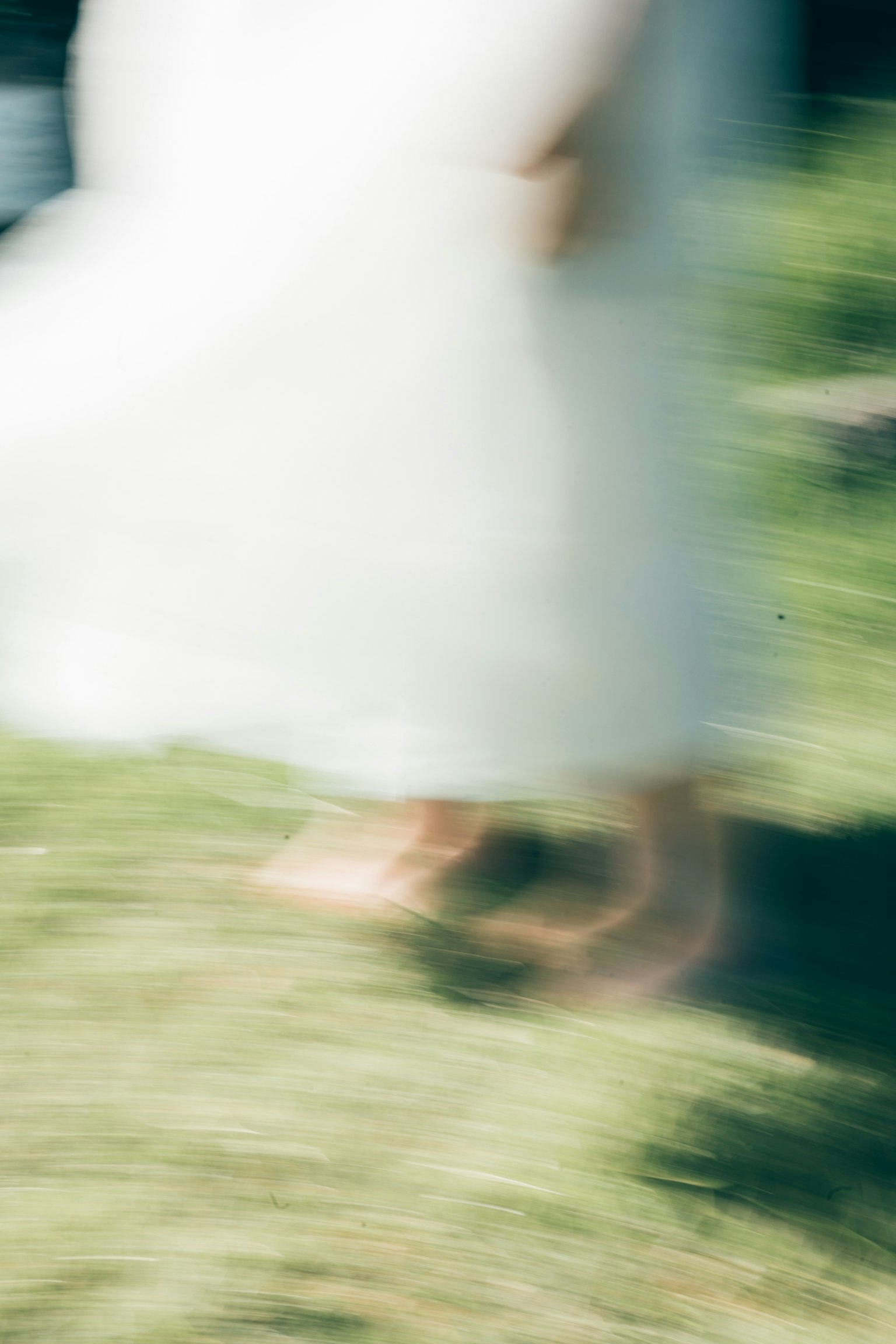 Una imagen borrosa de una persona caminando sobre la hierba con un vestido blanco
