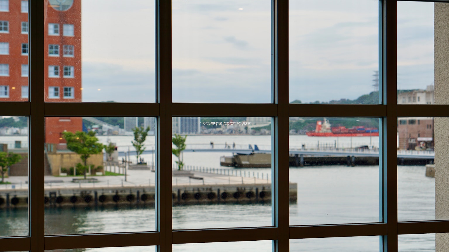 Blick auf einen Hafen durch ein Fenster mit Booten und ruhigem Wasser, nahegelegene Gebäude