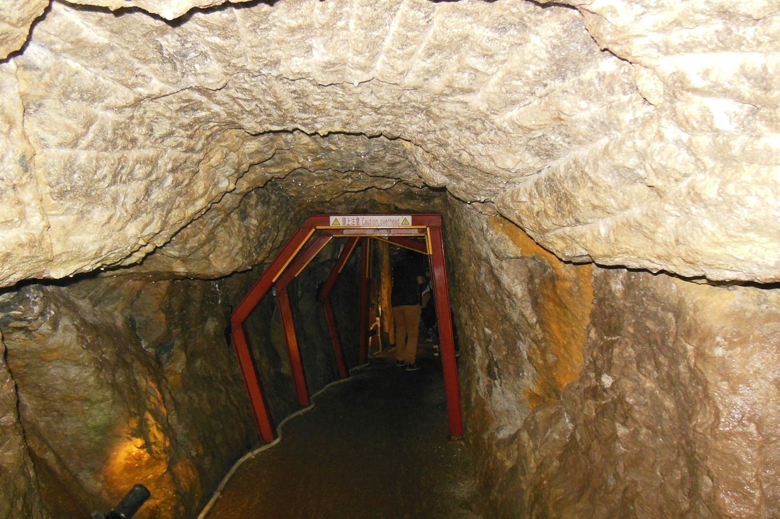 Interior of a tunnel with rock walls and a red framed doorway
