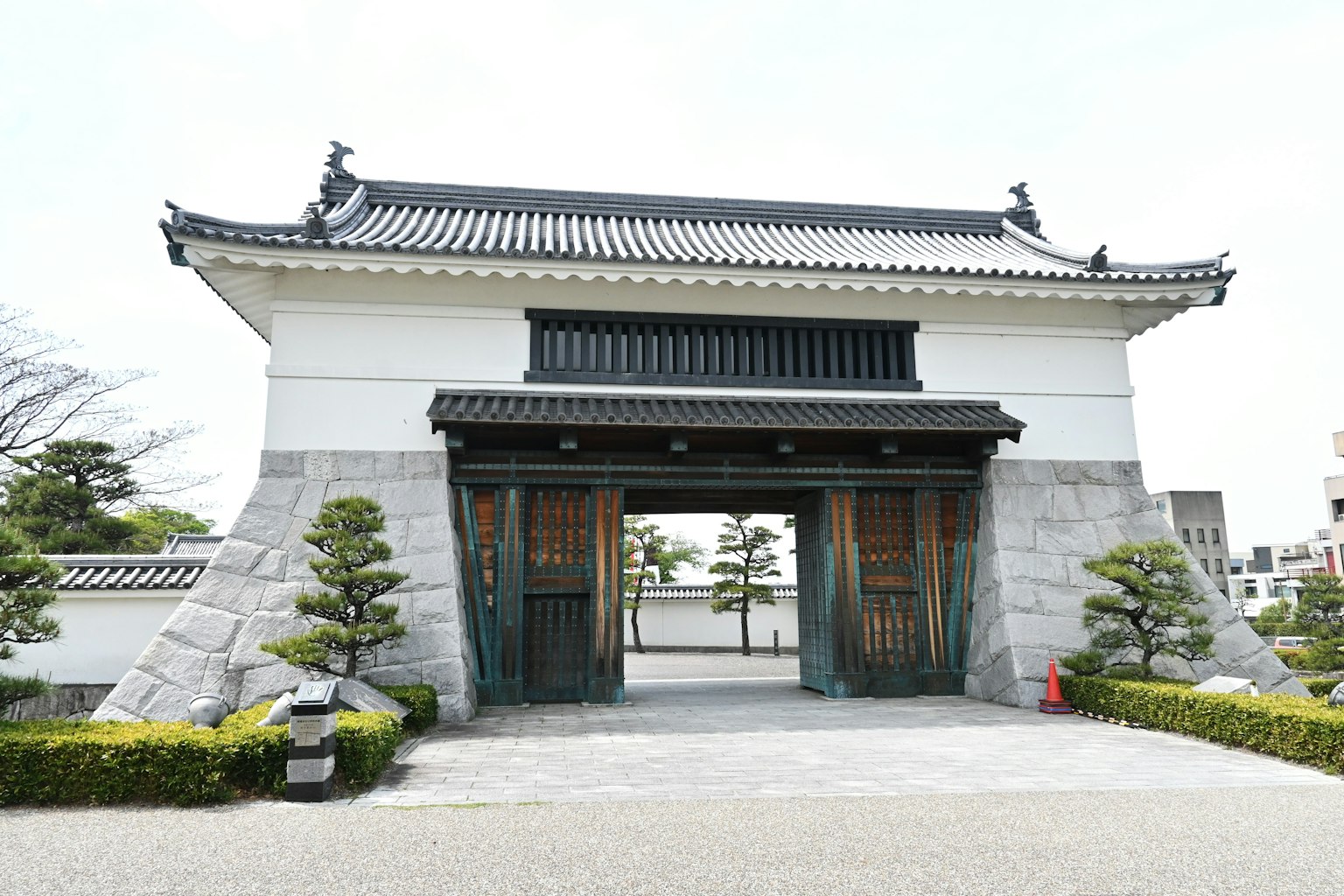 傳統日本門，白色牆壁和黑色屋頂，帶有植物和石頭裝飾