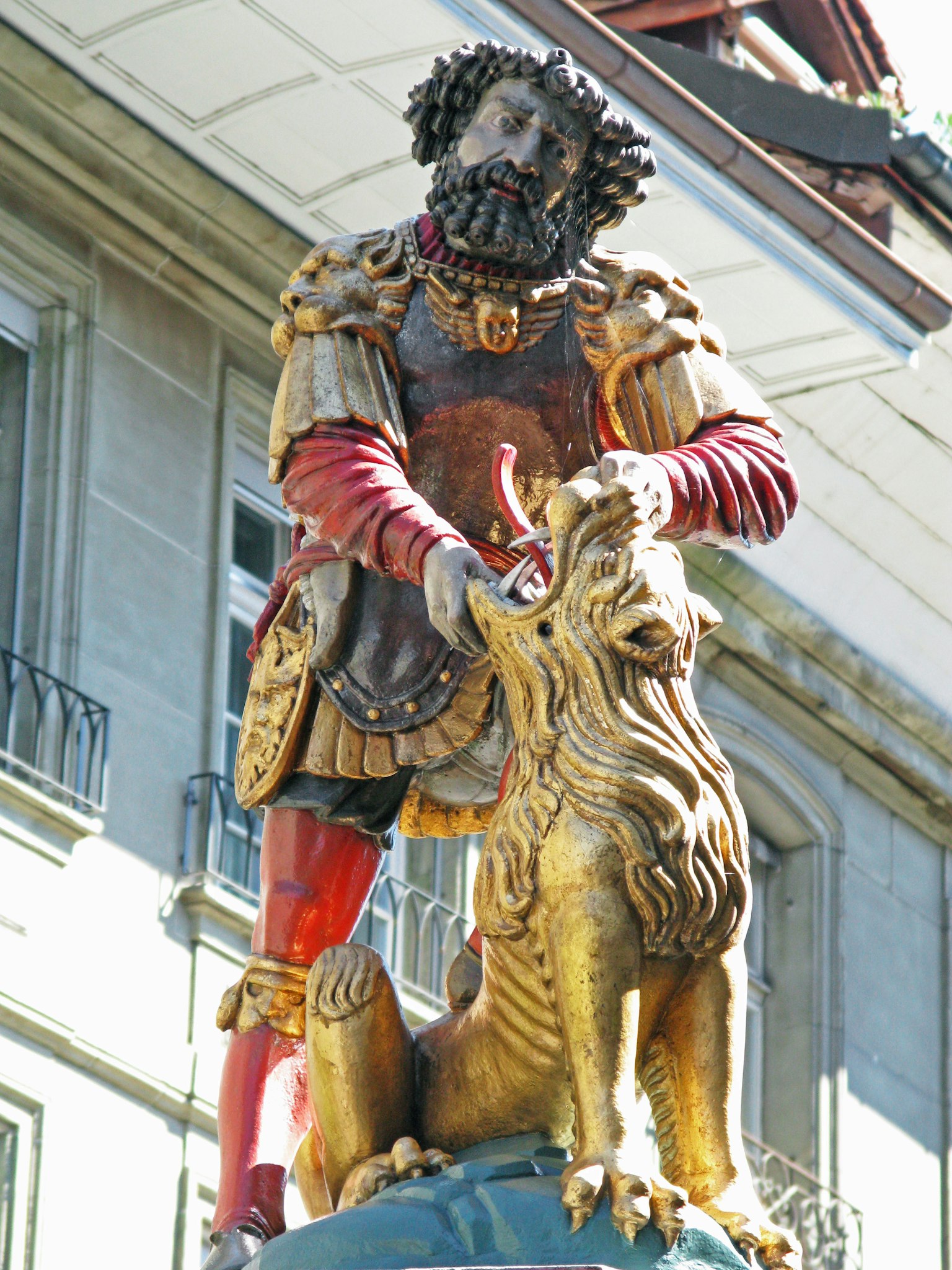 Estatua de un guerrero sosteniendo un león dorado