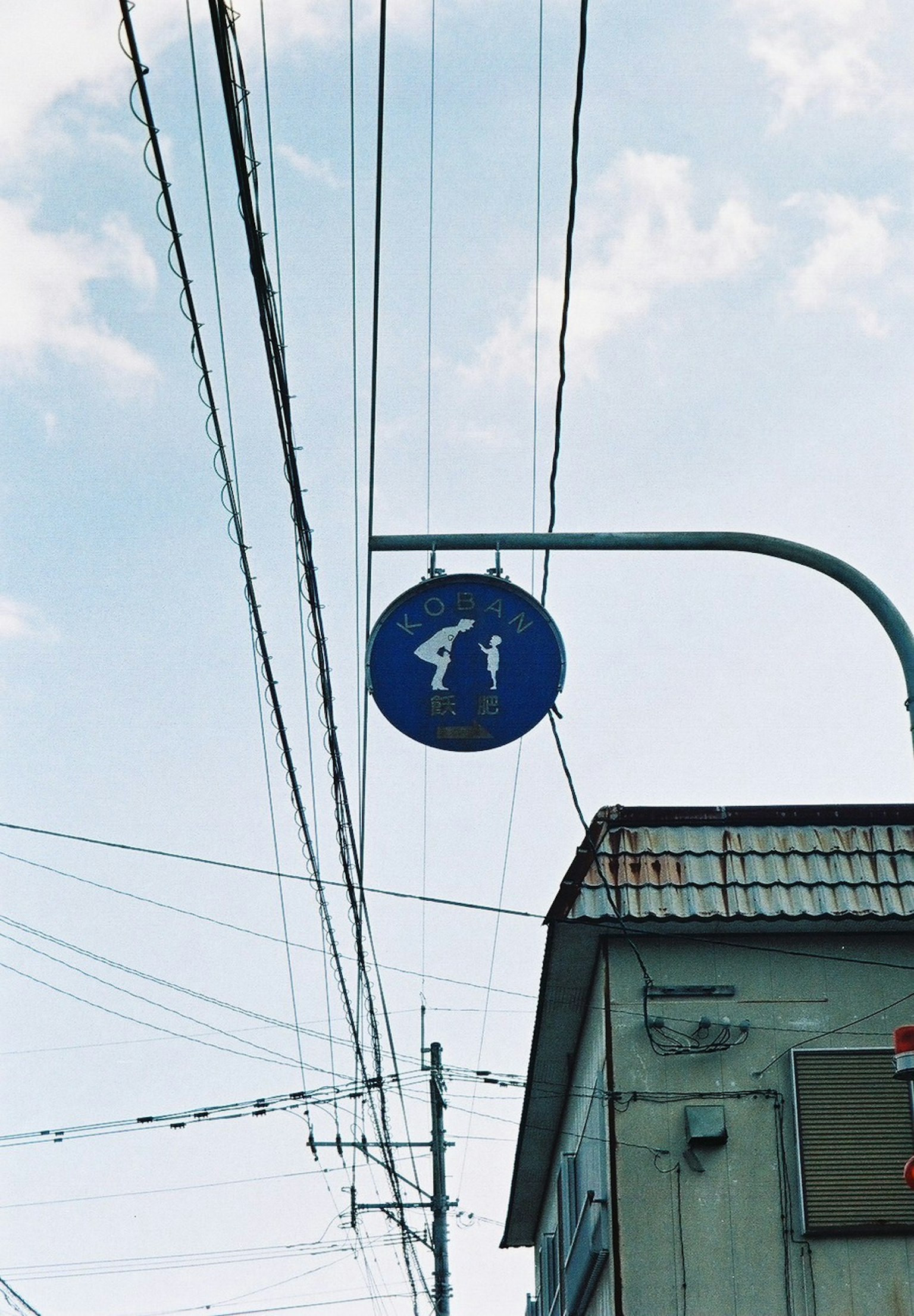 Blue pedestrian signal sign against a cloudy sky