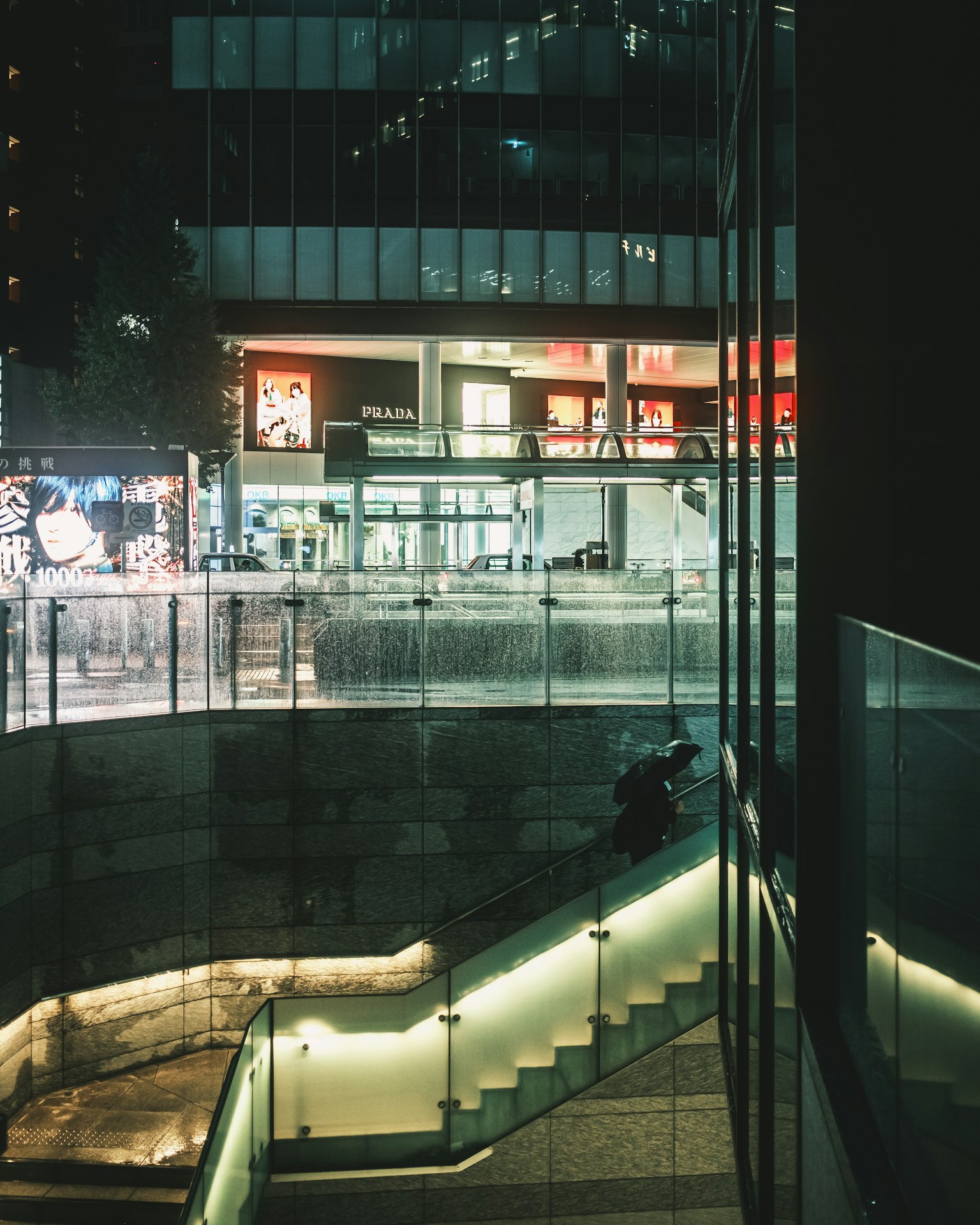 Exterior of a glass building at night featuring illuminated stairs