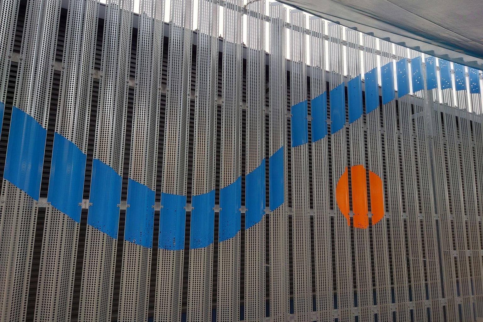 Metal fence featuring a blue wave design and an orange circle