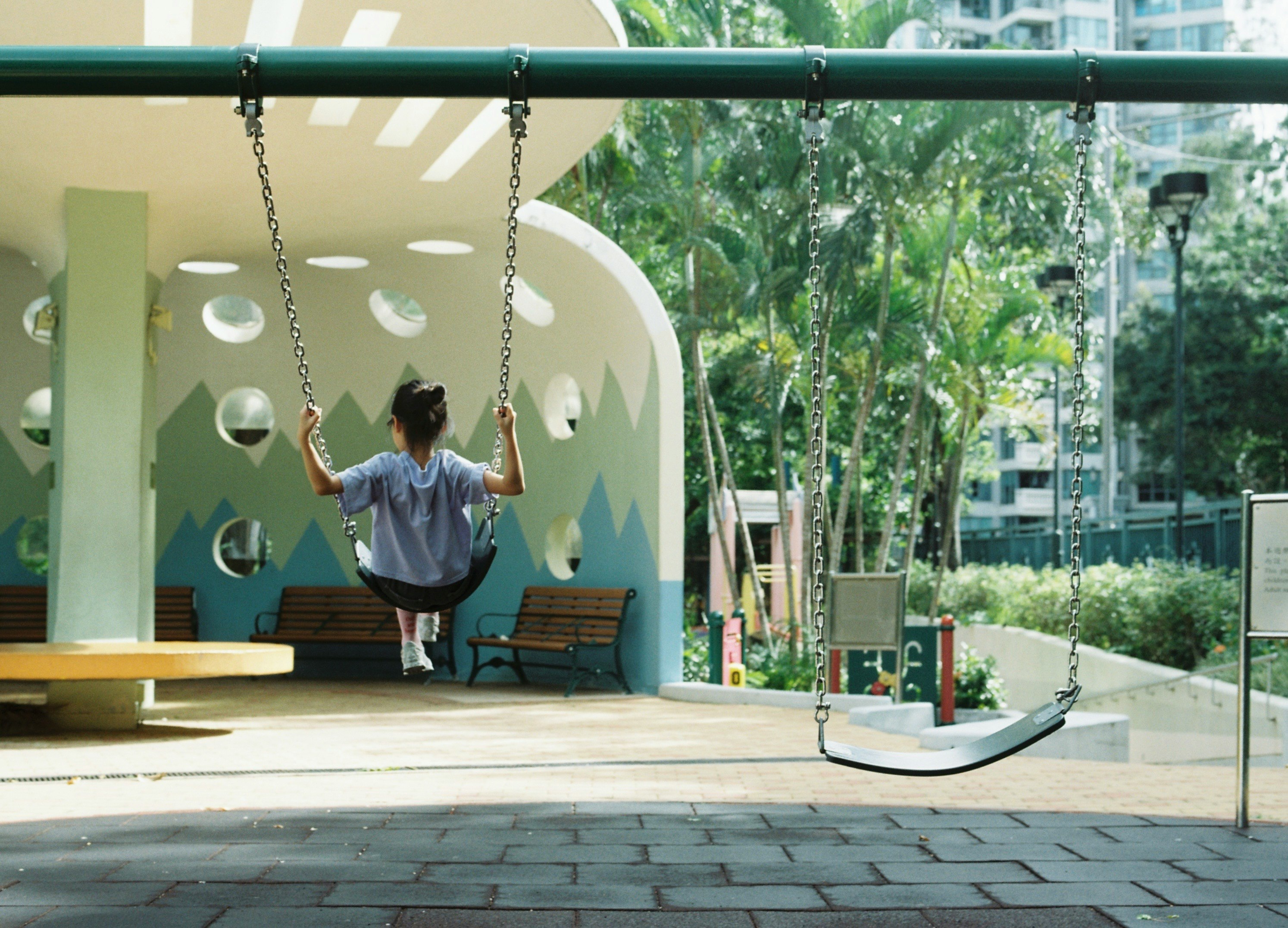 Kind, das an einem Outdoor-Spielgerät in einem Innenhof hängt
