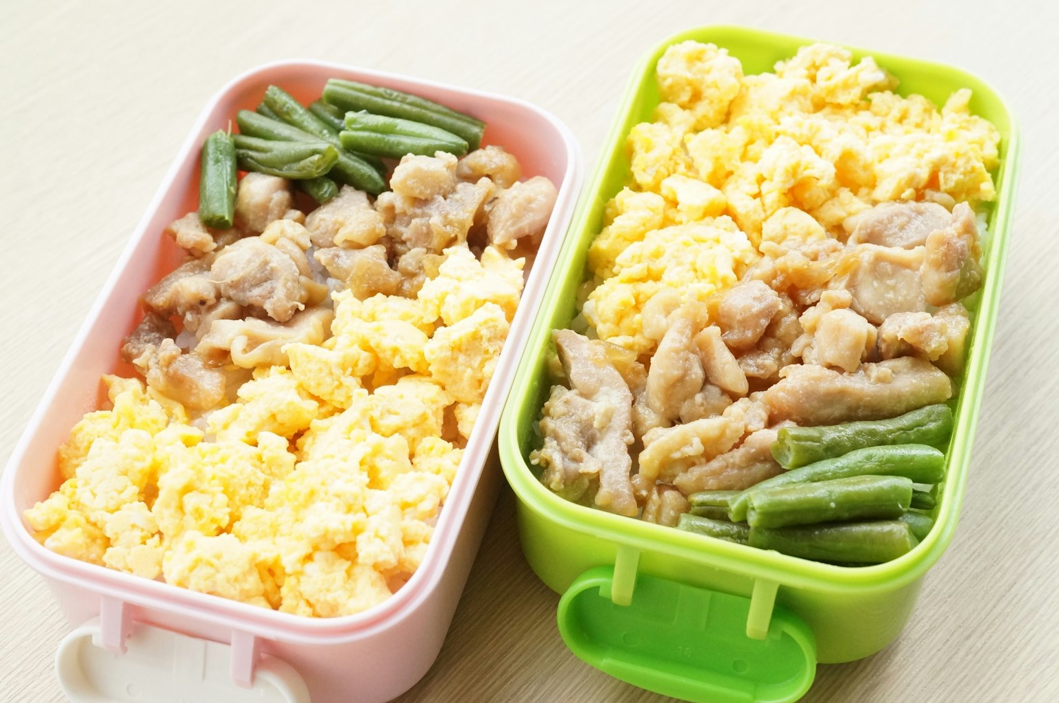 两个便当盒内含炒蛋鸡肉和青豆