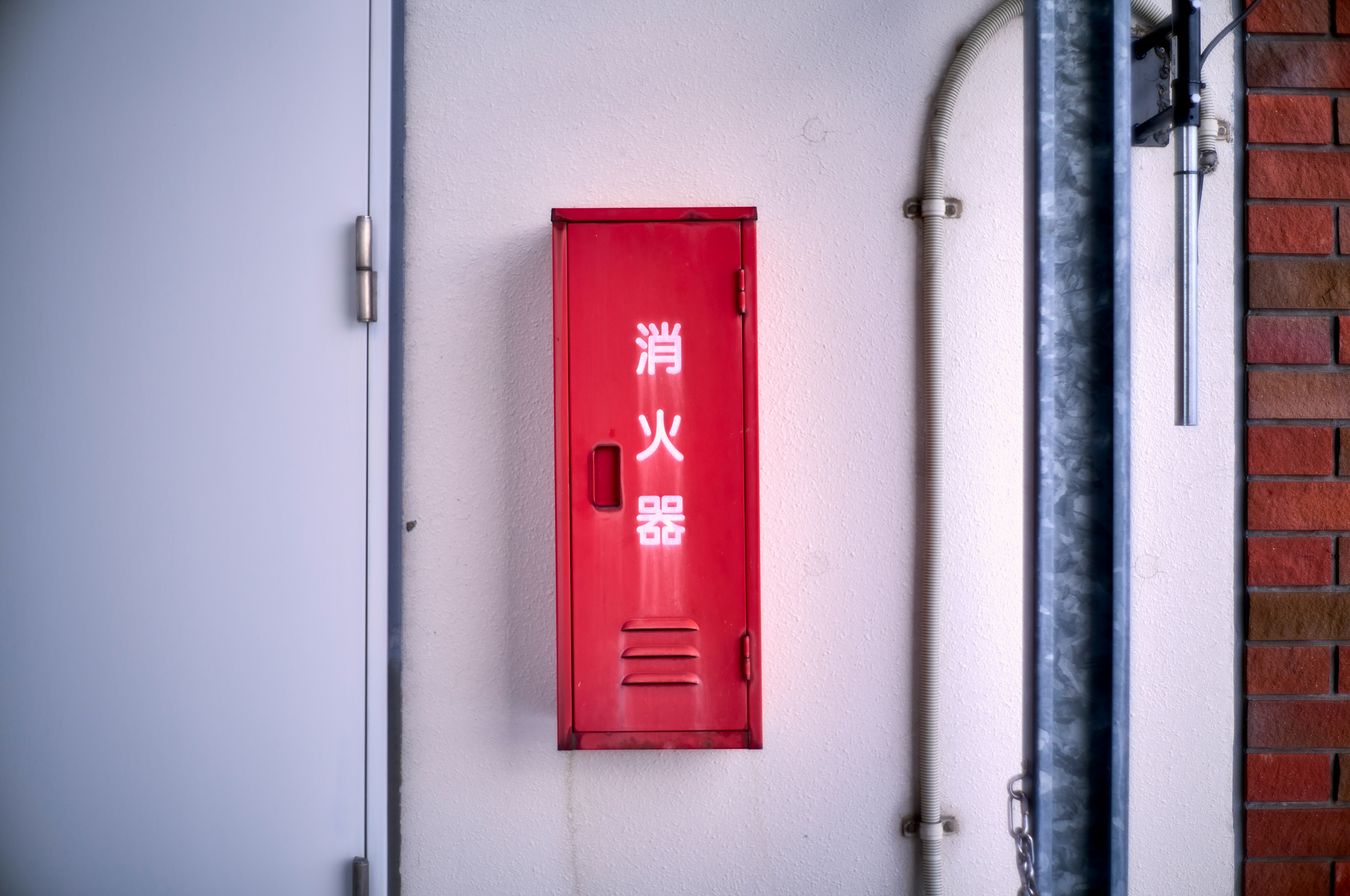 赤い消火器ボックスが壁に取り付けられた建物の外観