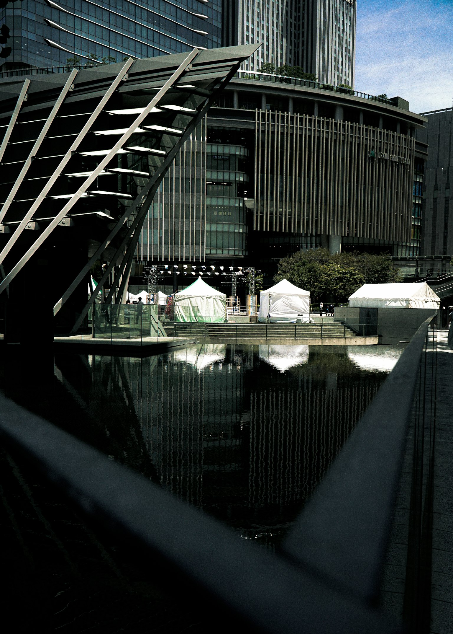 Reflection of modern buildings on a calm water surface with tents