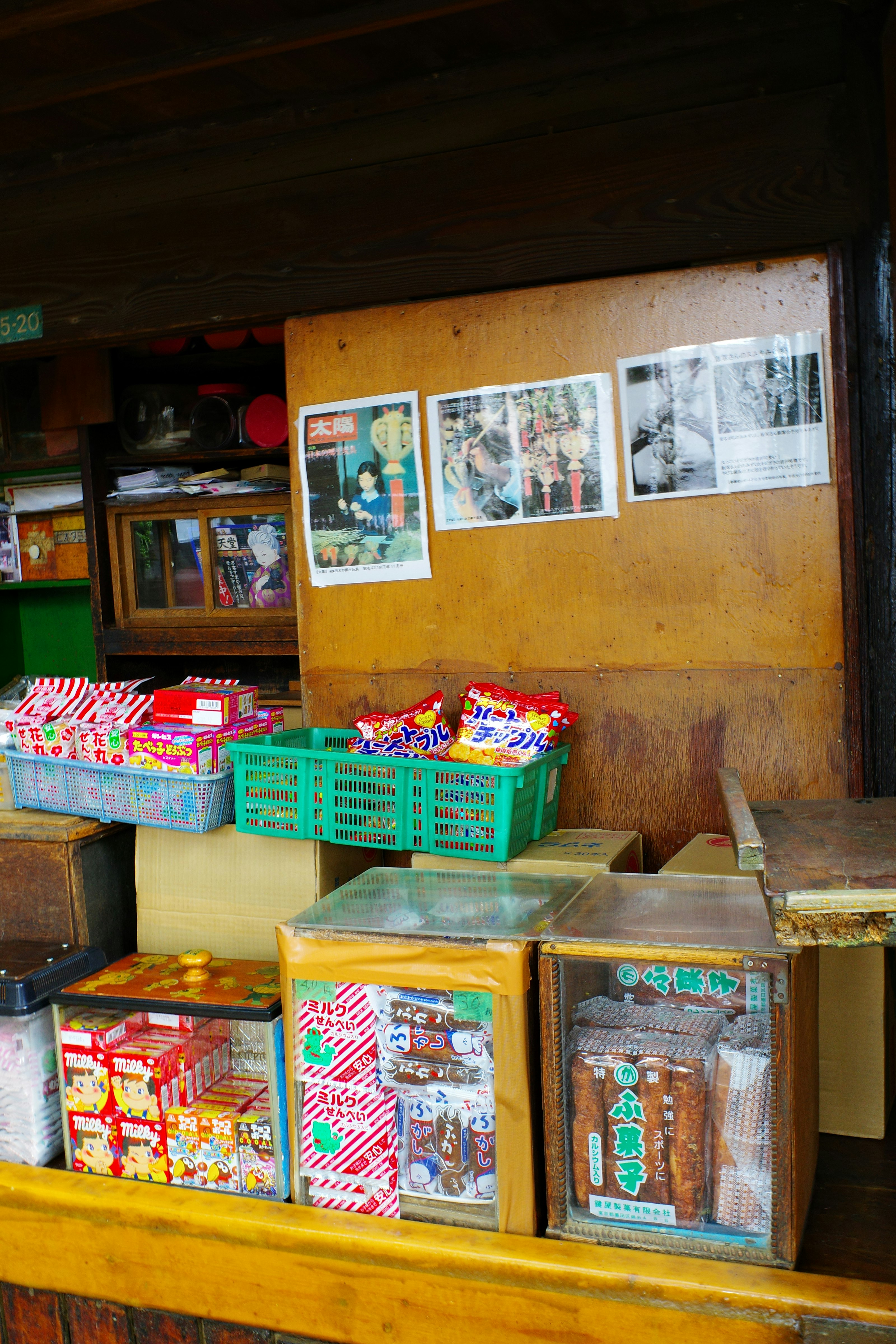 軒先に並ぶカラフルなお菓子の屋台と店内ポスターのある商店街の一角