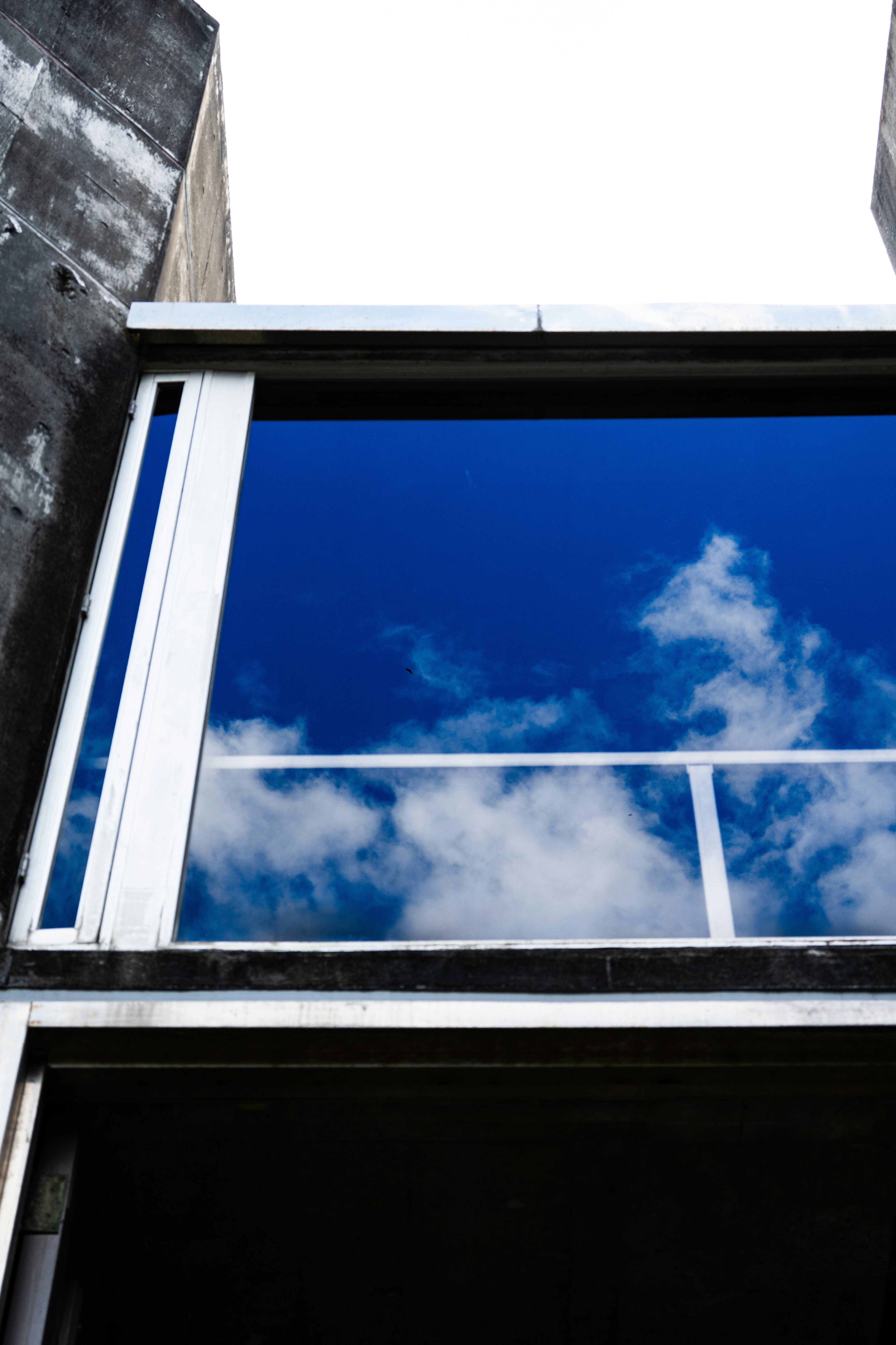 langit biru dan awan terlihat melalui bingkai jendela gedung