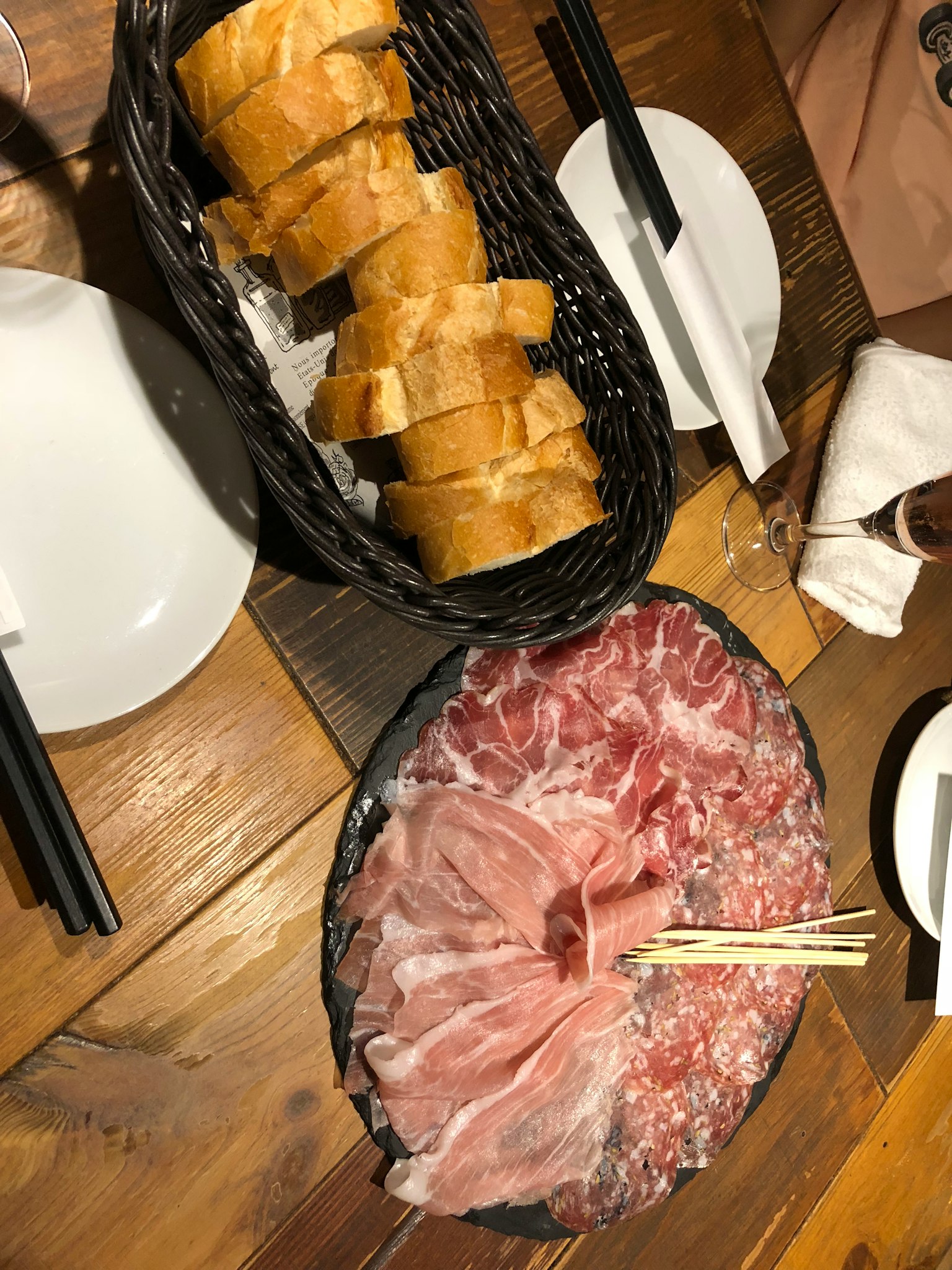 Viande séchée tranchée sur une assiette noire avec un panier de pain