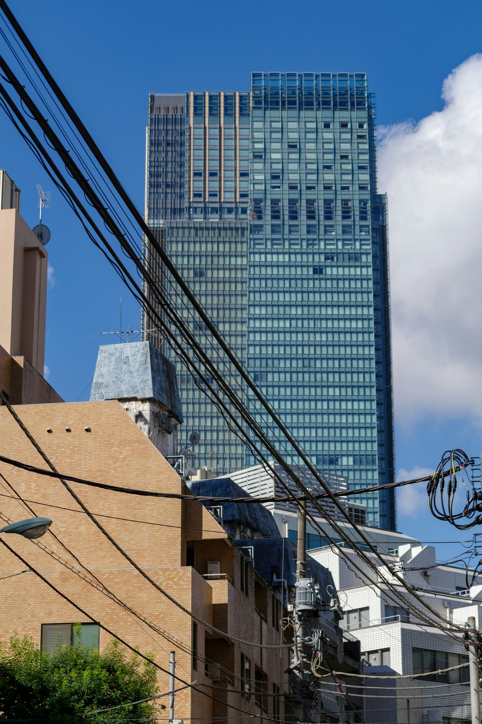 Urban landscape featuring a tall skyscraper and surrounding buildings with power lines