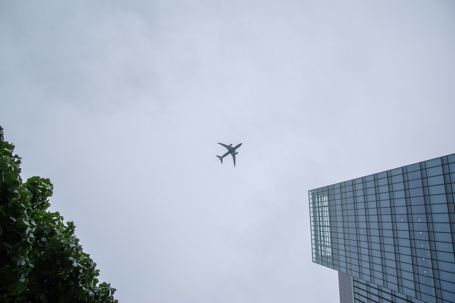 Ein Flugzeug fliegt über einem hohen Gebäude unter einem bewölkten Himmel
