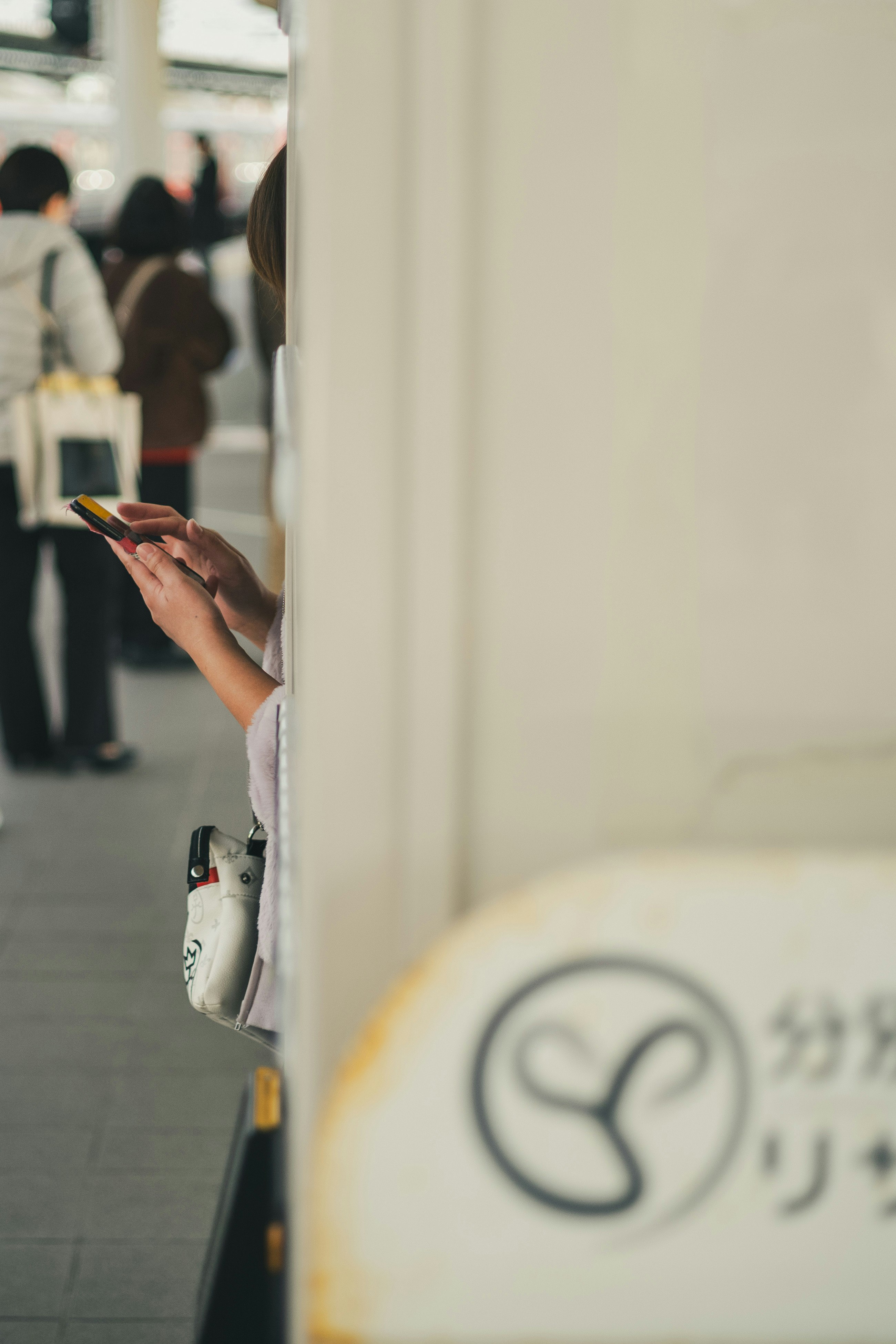 折尾駅前の路地でスマホを見ながら歩く人