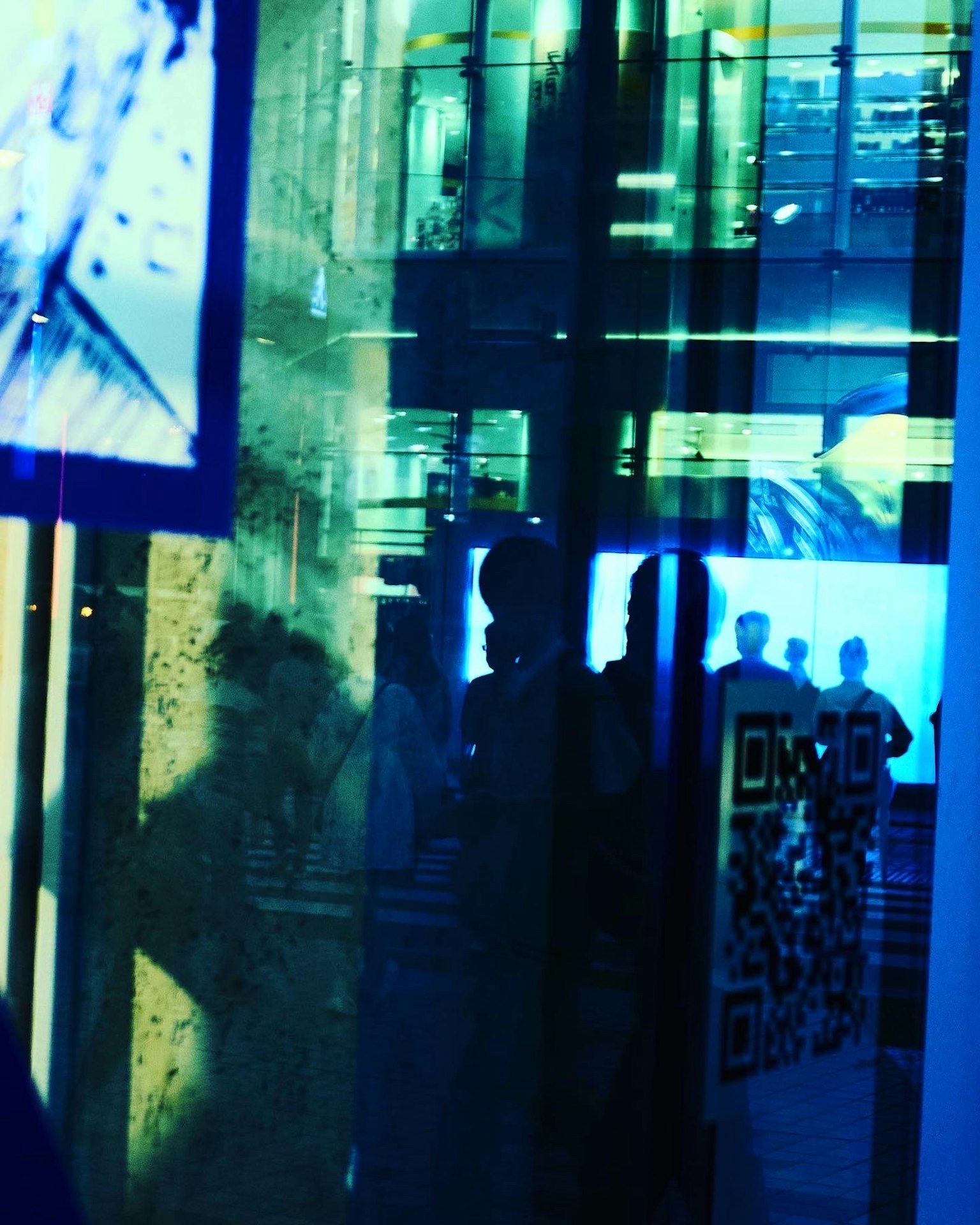 Siluetas de personas reflejadas en luz azul con un código QR visible