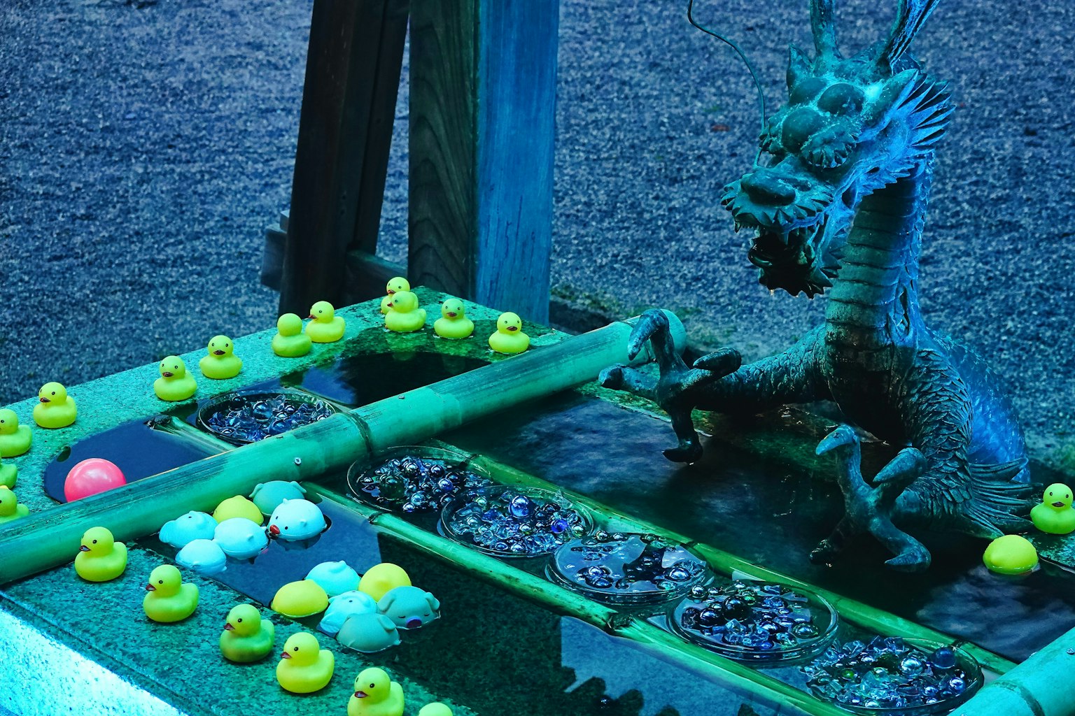 Statua di drago in luce blu con anatre di gomma gialle e bambù