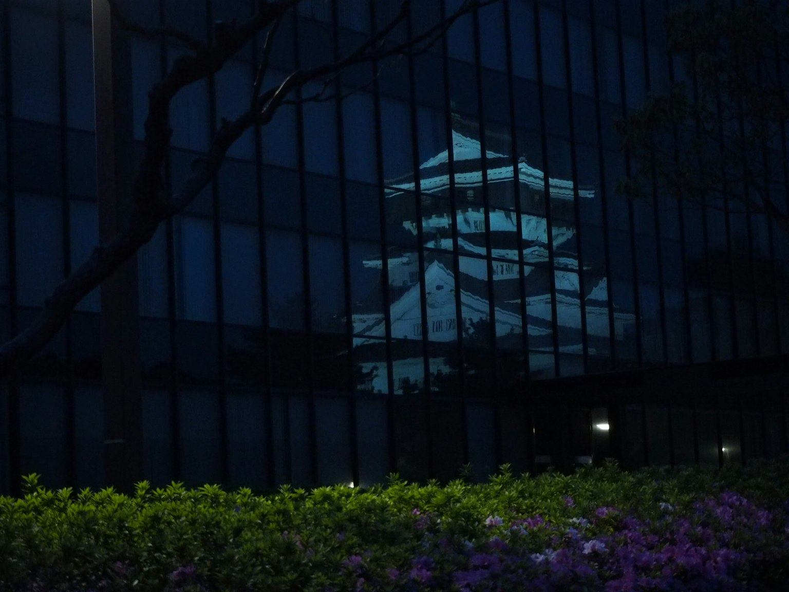 Reflet d'un château japonais traditionnel dans un bâtiment moderne la nuit