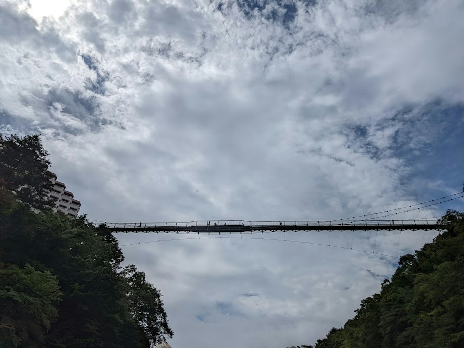 Un lungo ponte che attraversa una valle sotto un cielo nuvoloso con colline verdi