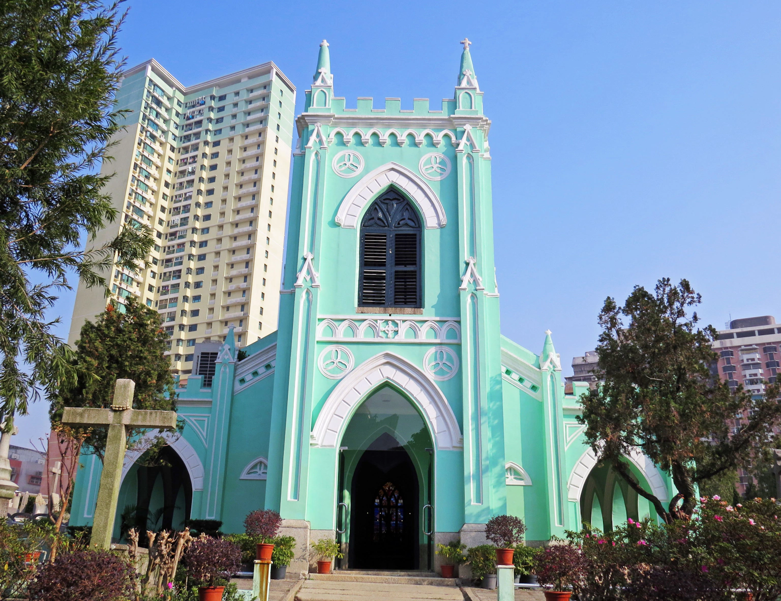 Église de style gothique de couleur turquoise à côté de grands immeubles modernes