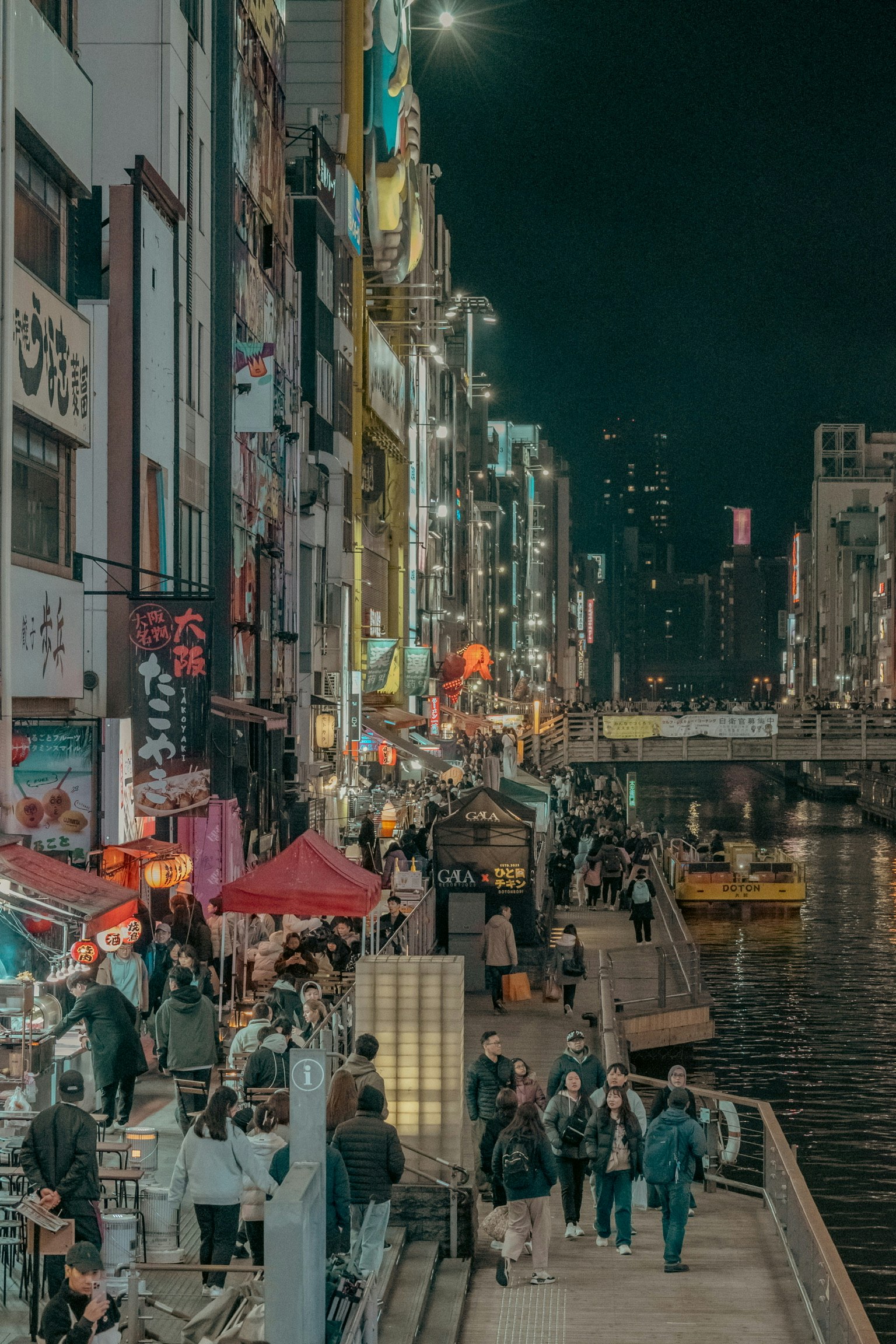 Lebhafte Nachtleben entlang des Flusses mit Neonlichtern und Menschenmengen