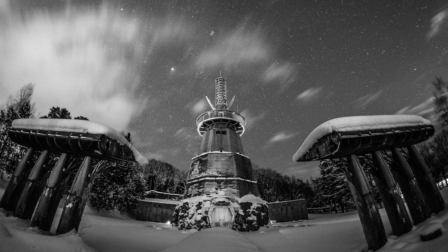Scena di torre e cancello coperti di neve con stelle brillanti nel cielo notturno