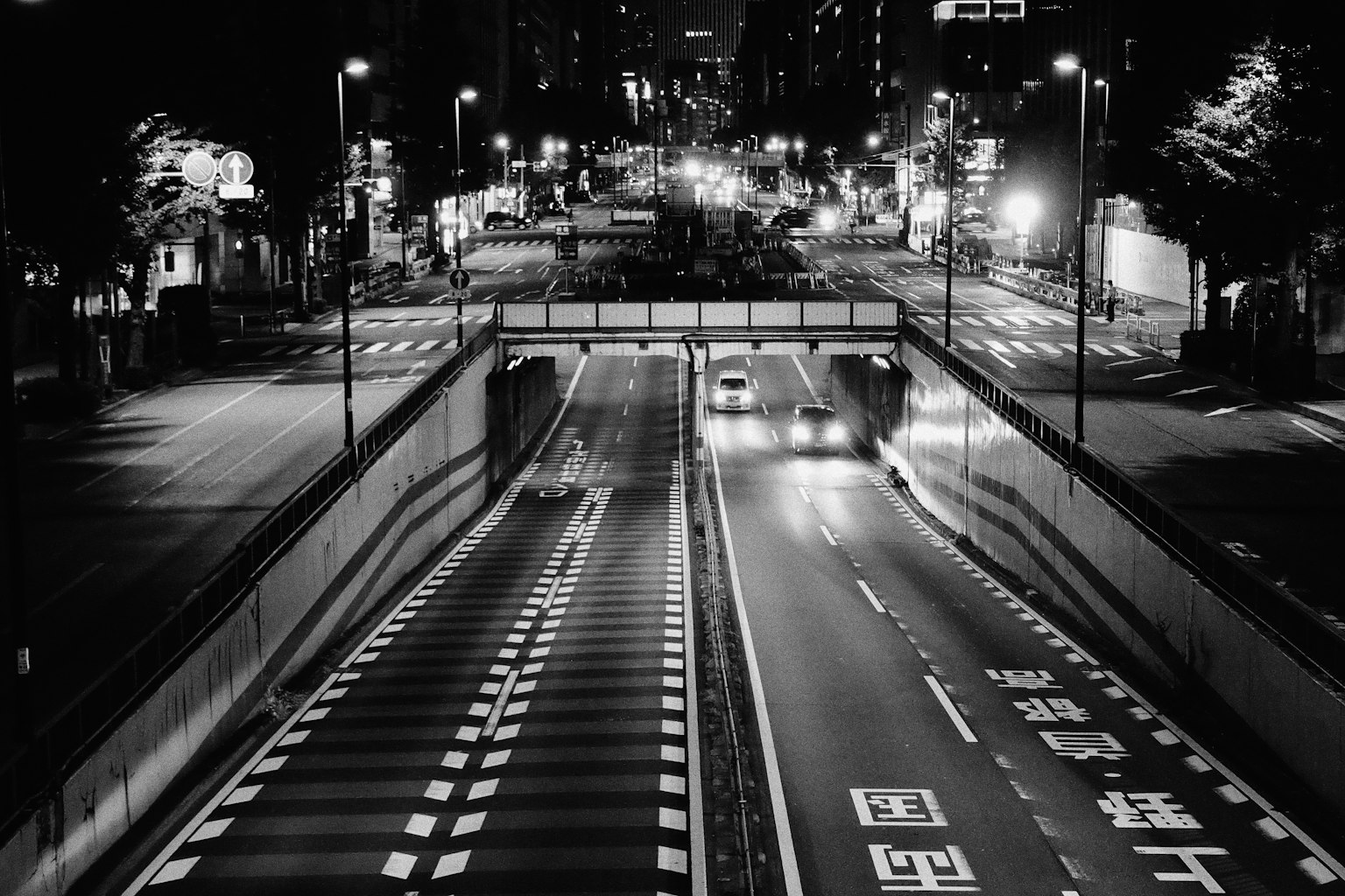夜の都市の交差点とトンネルの風景 車両が走行する白黒の道路
