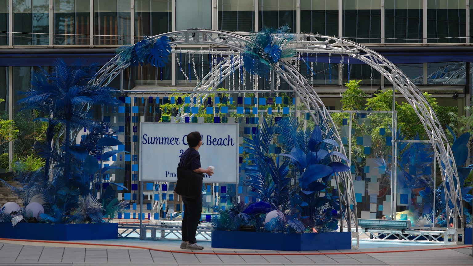 Person standing under a blue decorative arch with floral elements