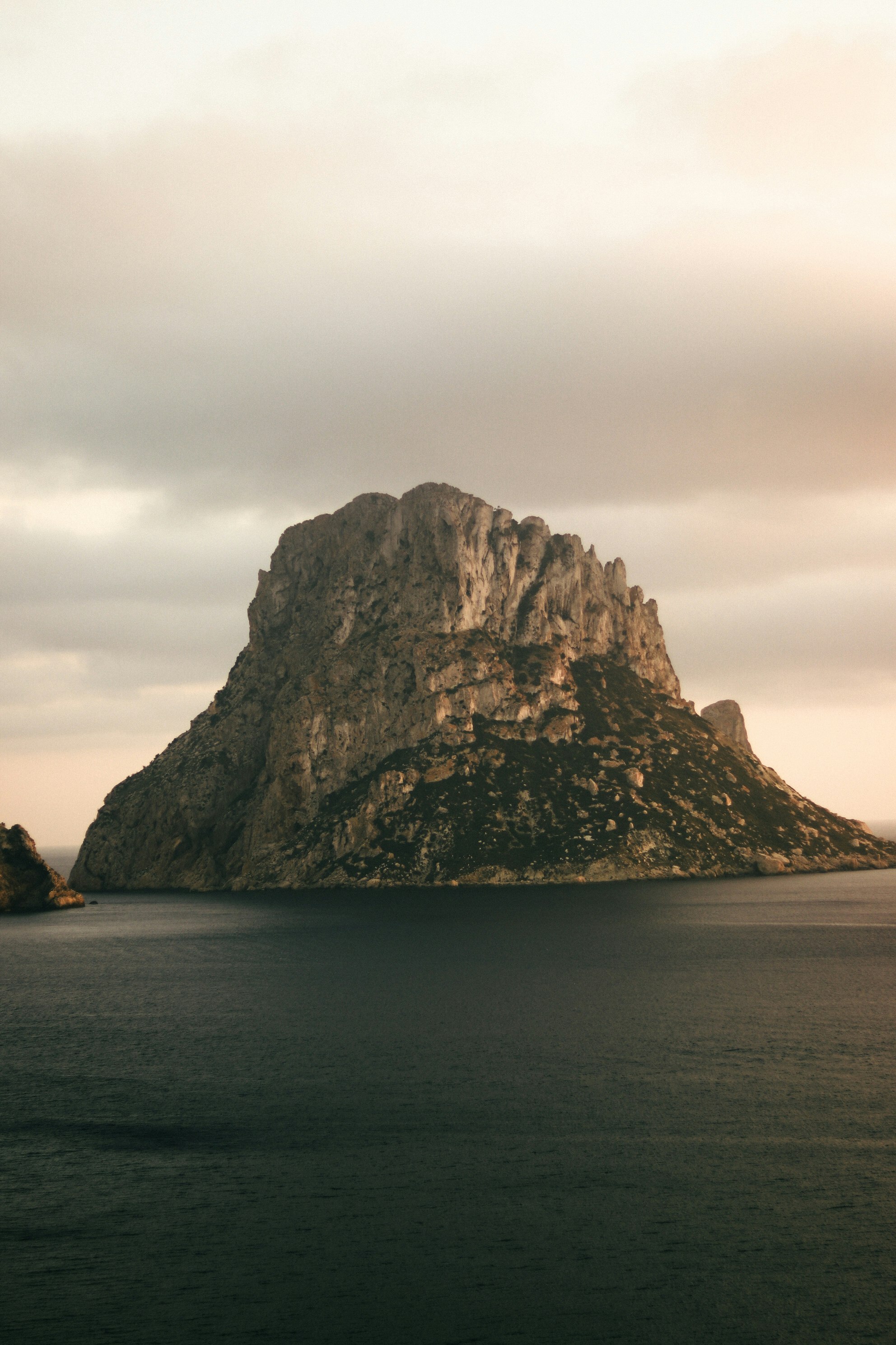 paesaggio costiero al crepuscolo con isola rocciosa e montagna