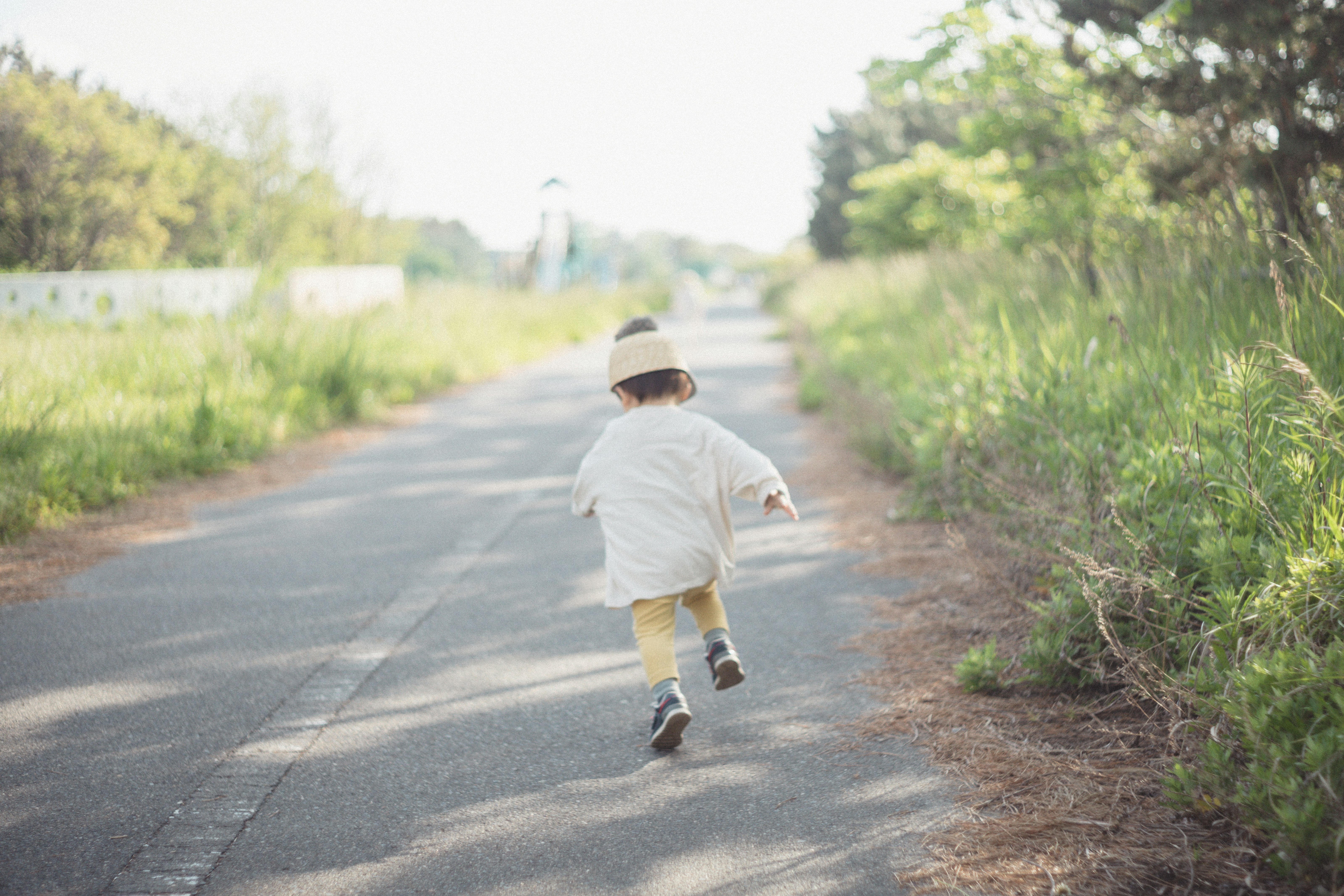 Child running down a path surrounded by grass and trees