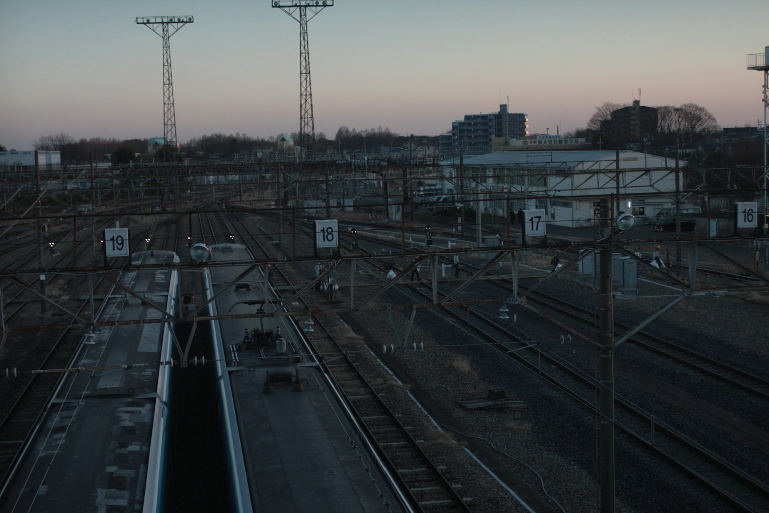 Twilight railway scene with multiple tracks and power poles visible