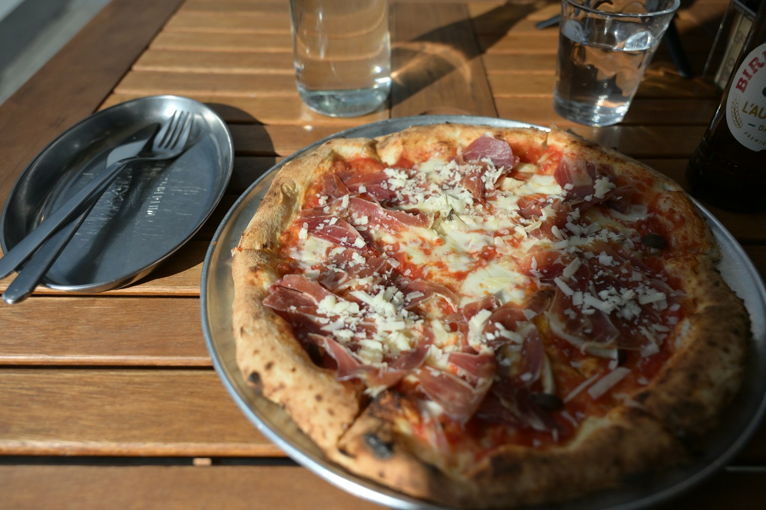 Pizza với phô mai và salami trên bàn gỗ có đồ uống