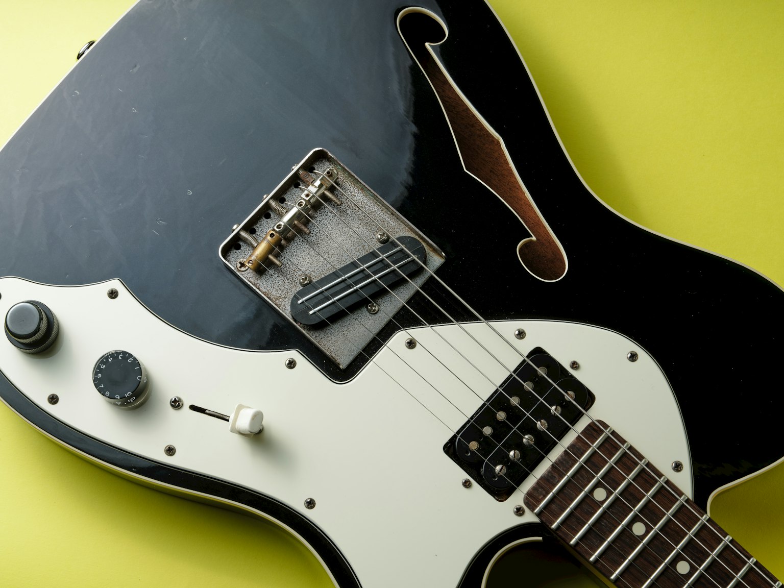 Guitare électrique noire et blanche en gros plan sur un fond jaune