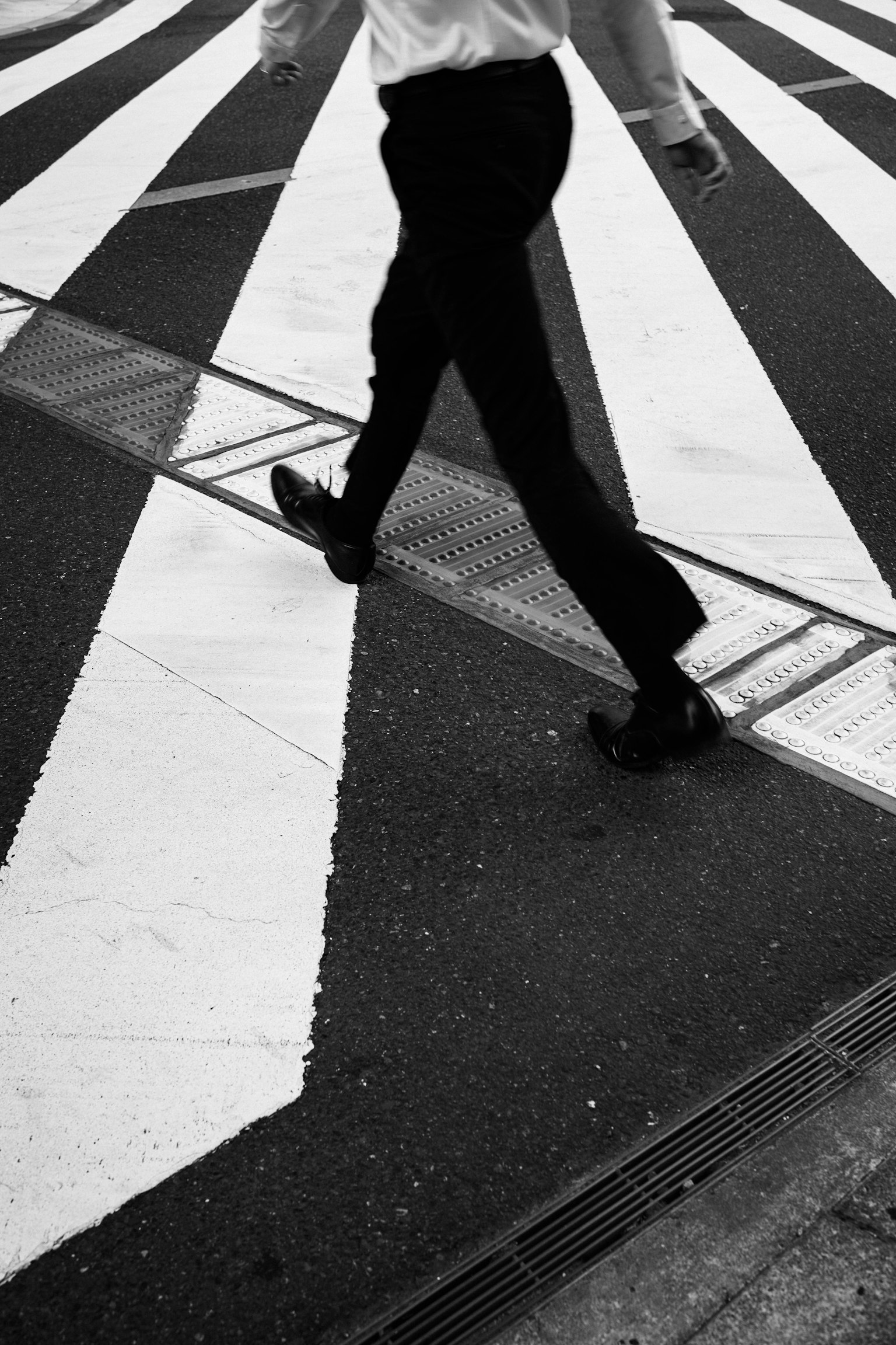 Die Füße eines Mannes, der auf einem schwarz-weißen Zebrastreifen geht