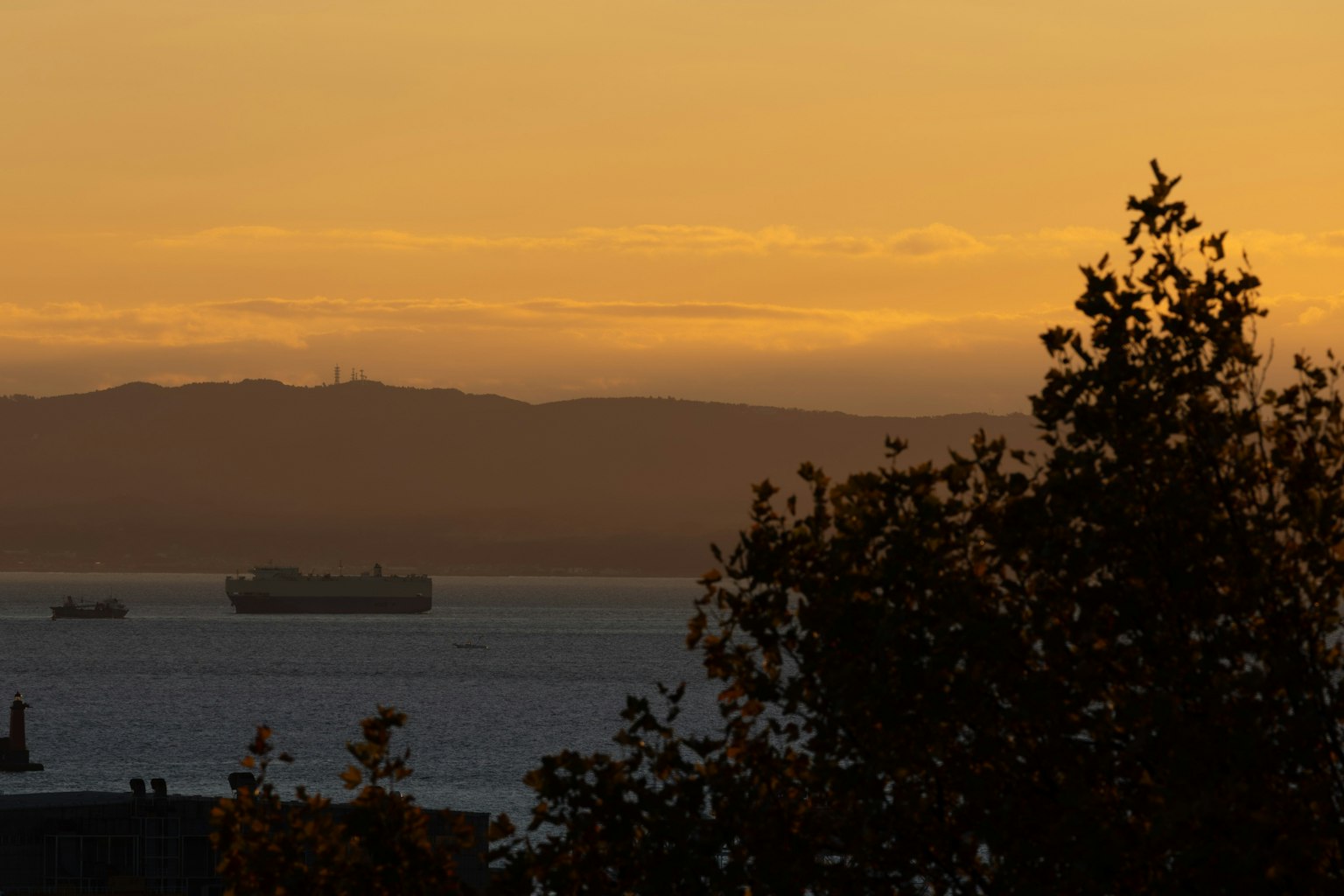 Silueta de barcos de carga en el mar durante el atardecer con montañas al fondo