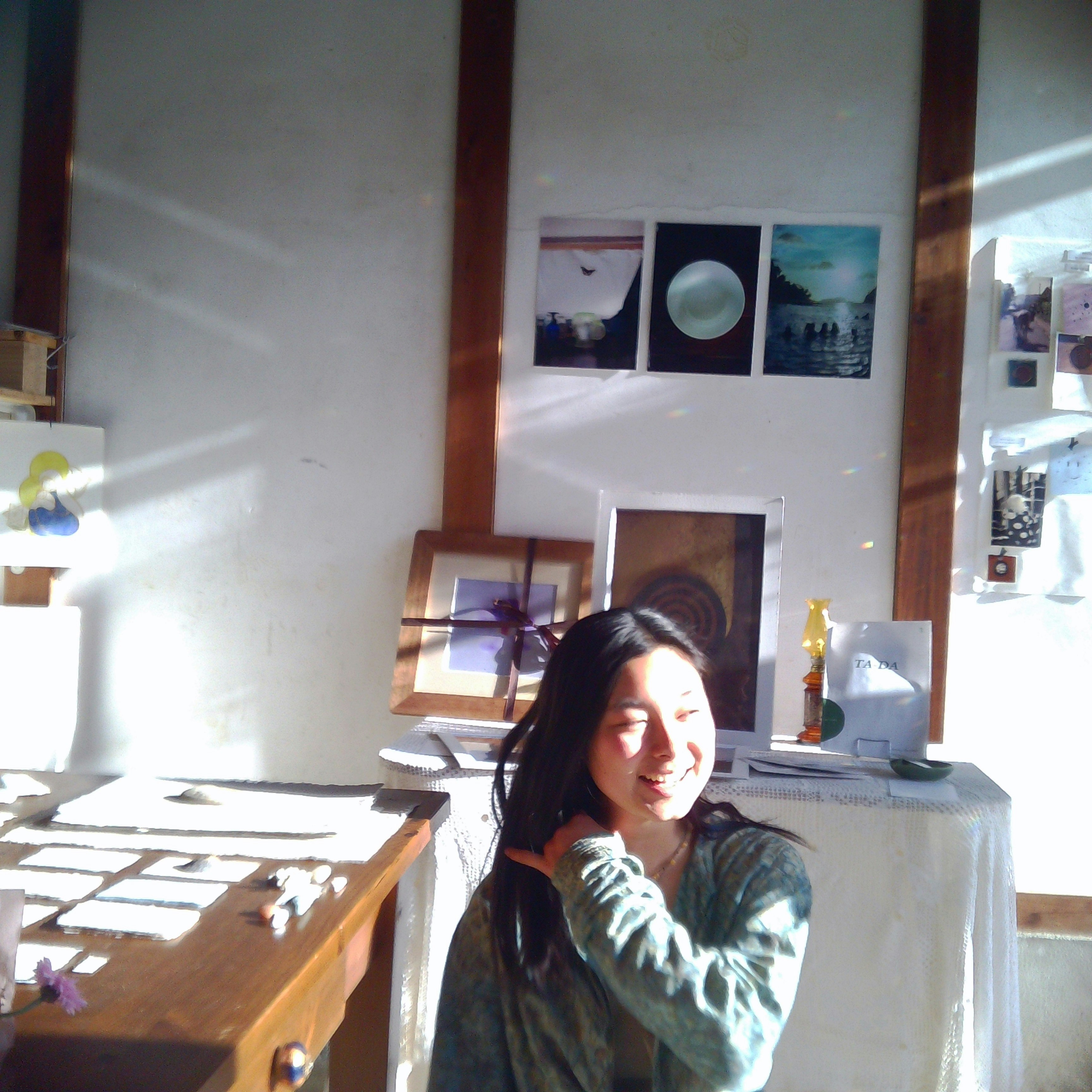 Una donna che sorride in una stanza luminosa con opere d'arte e poster sulle pareti