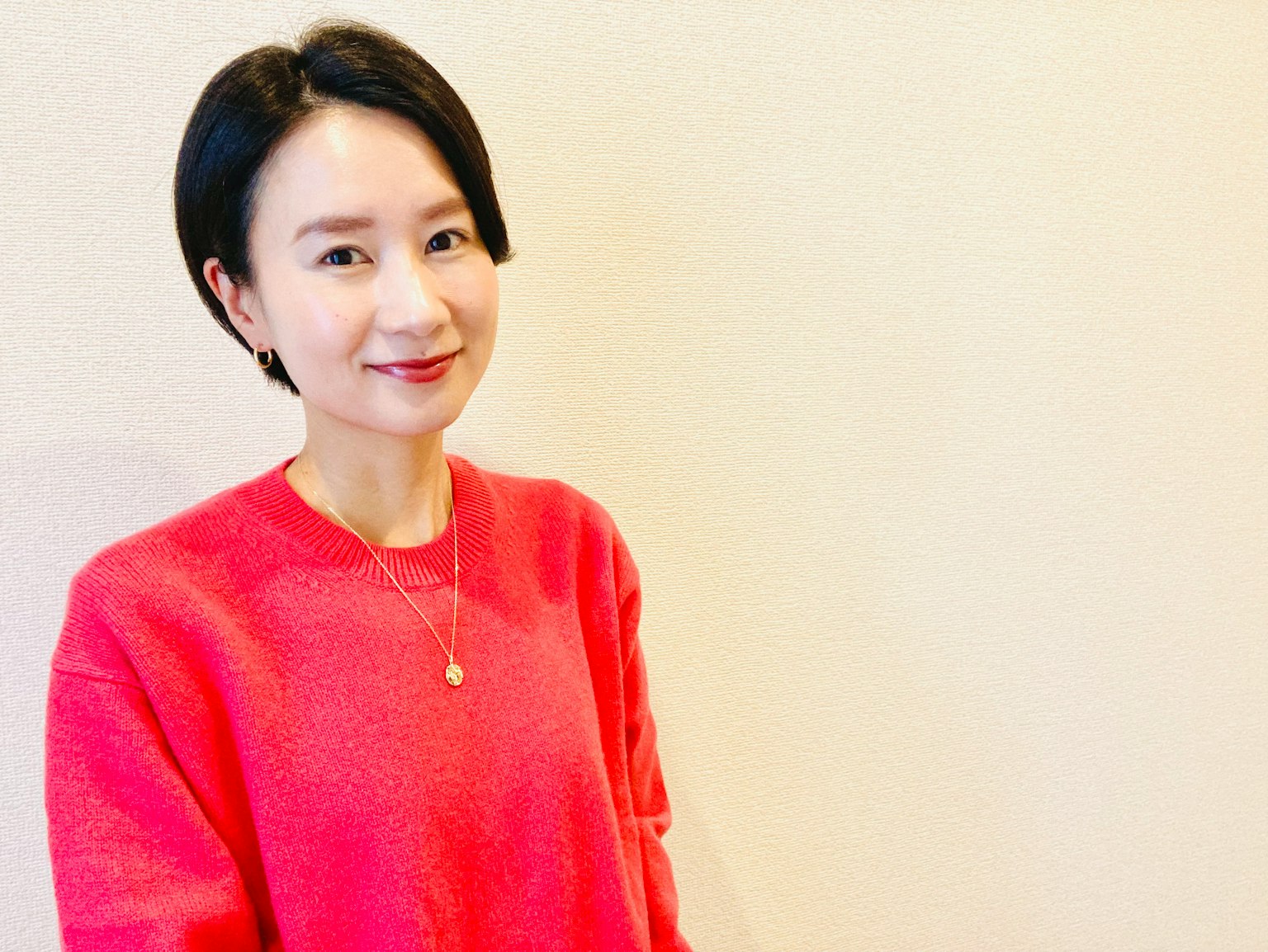 A woman in a bright red sweater smiling against a simple background