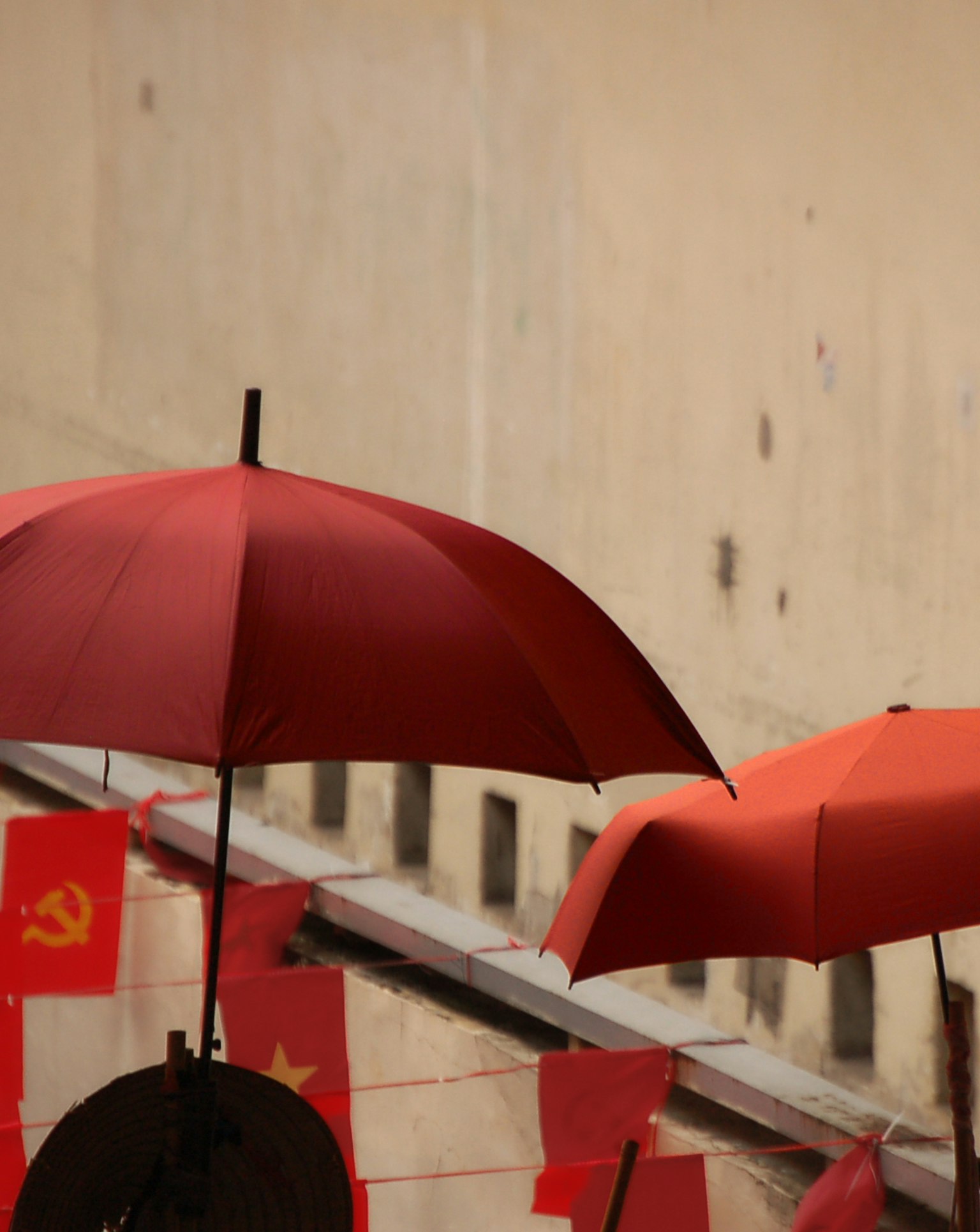 Sombrillas rojas con banderas comunistas exhibidas contra una pared