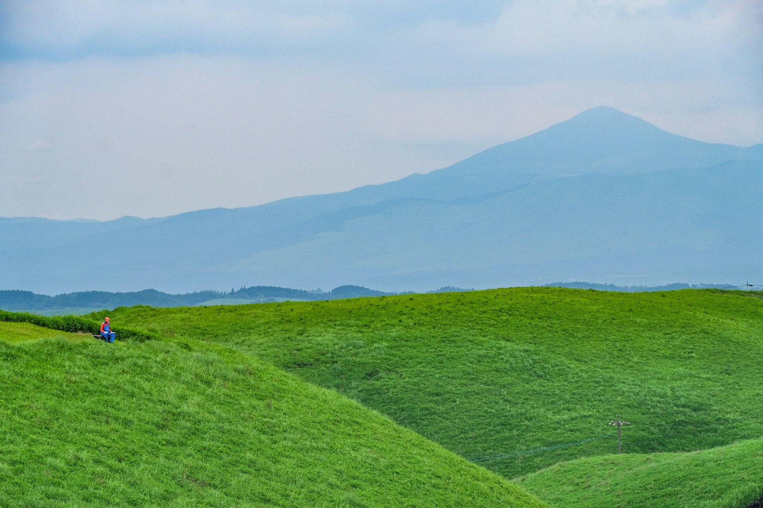 Lush green hills with distant mountains in a serene landscape