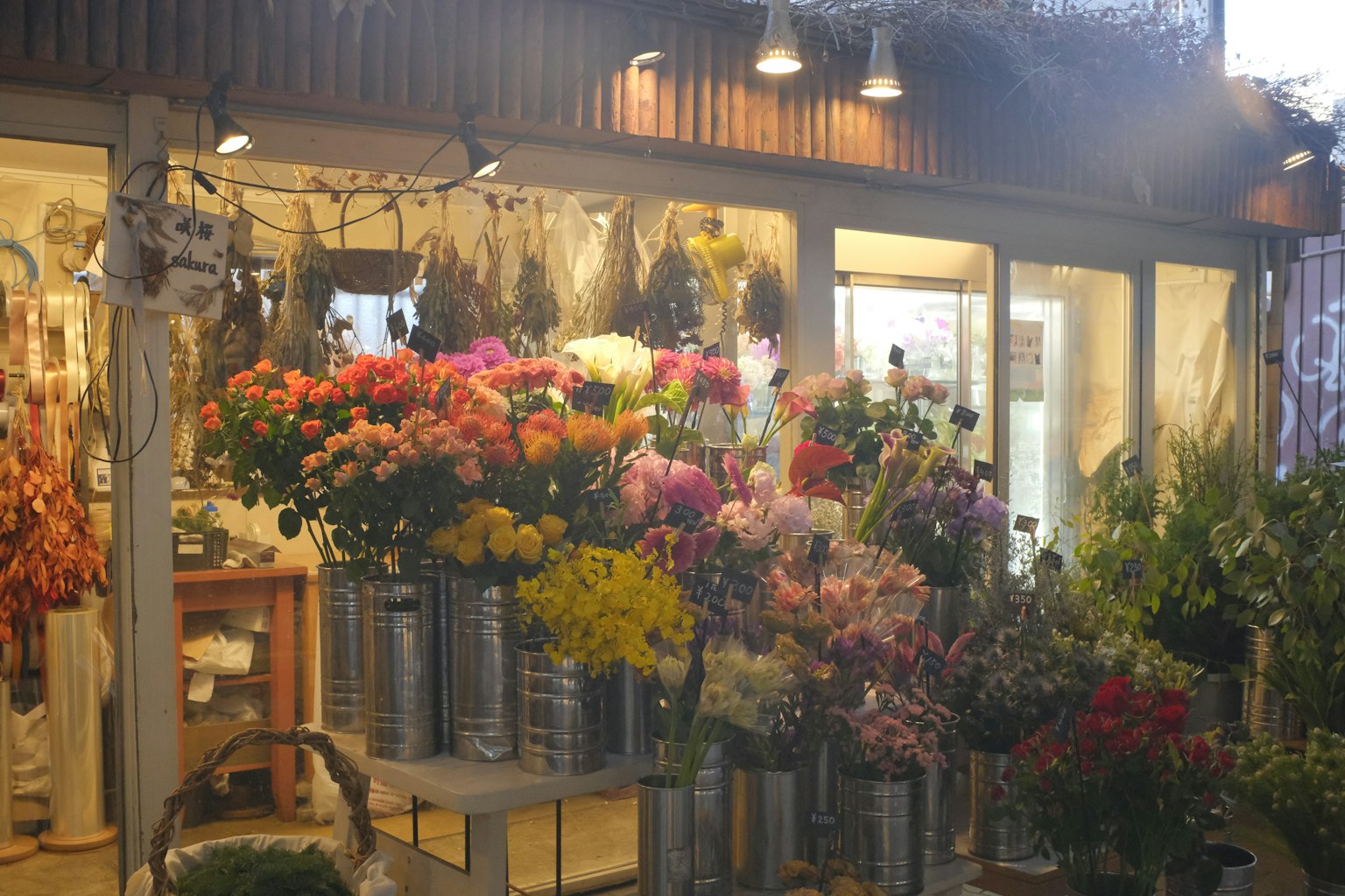 ภายนอกของร้านดอกไม้ที่มีดอกไม้หลากสีและแสงที่อบอุ่น