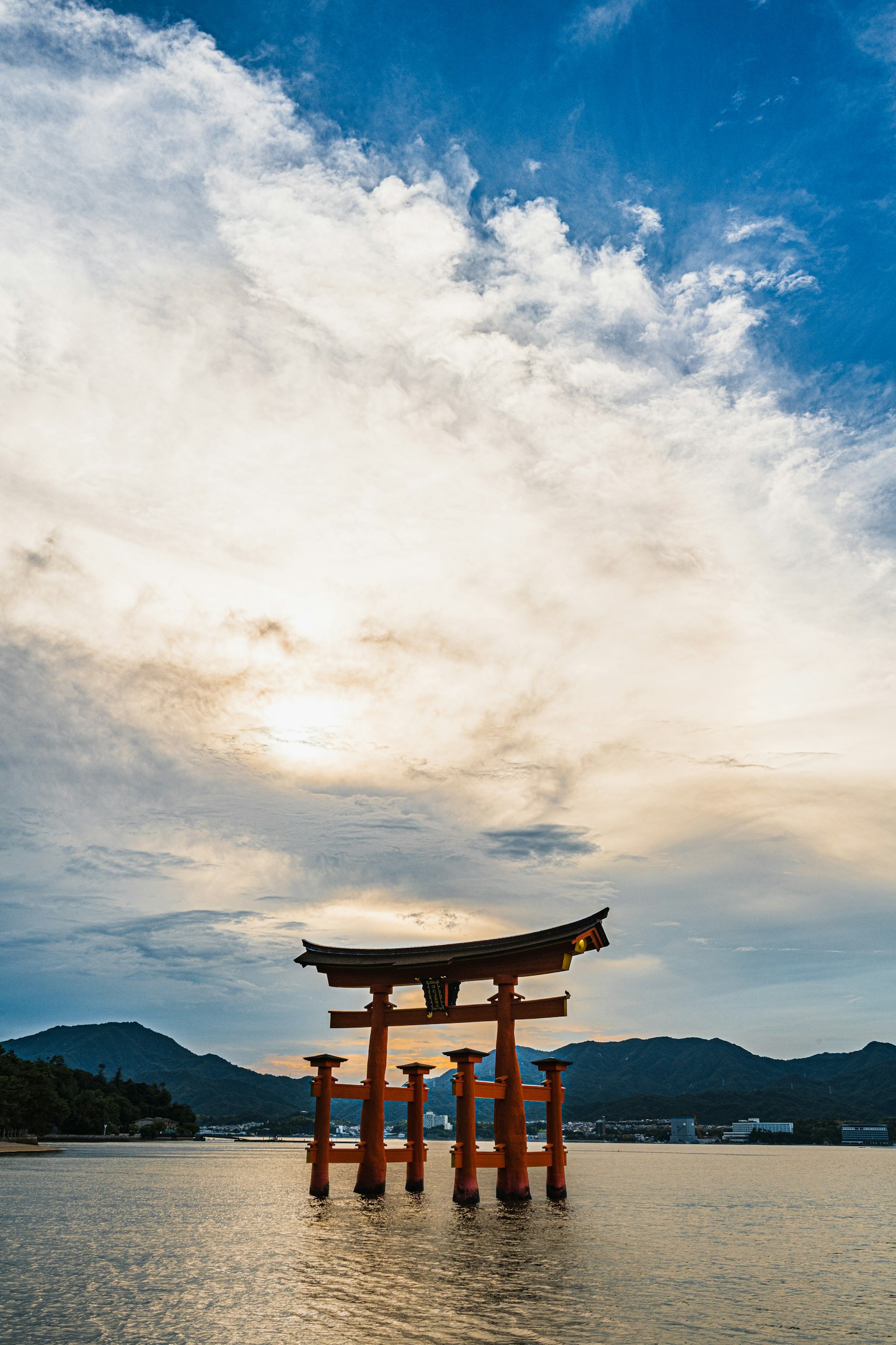 Torii gate of Itsukushima Shrine standing in water under a beautiful blue sky
