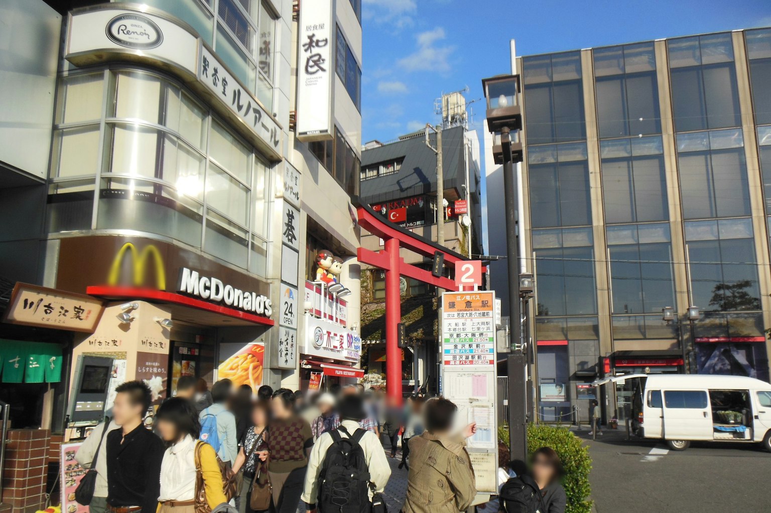 Busy street scene in Tokyo featuring a red torii gate