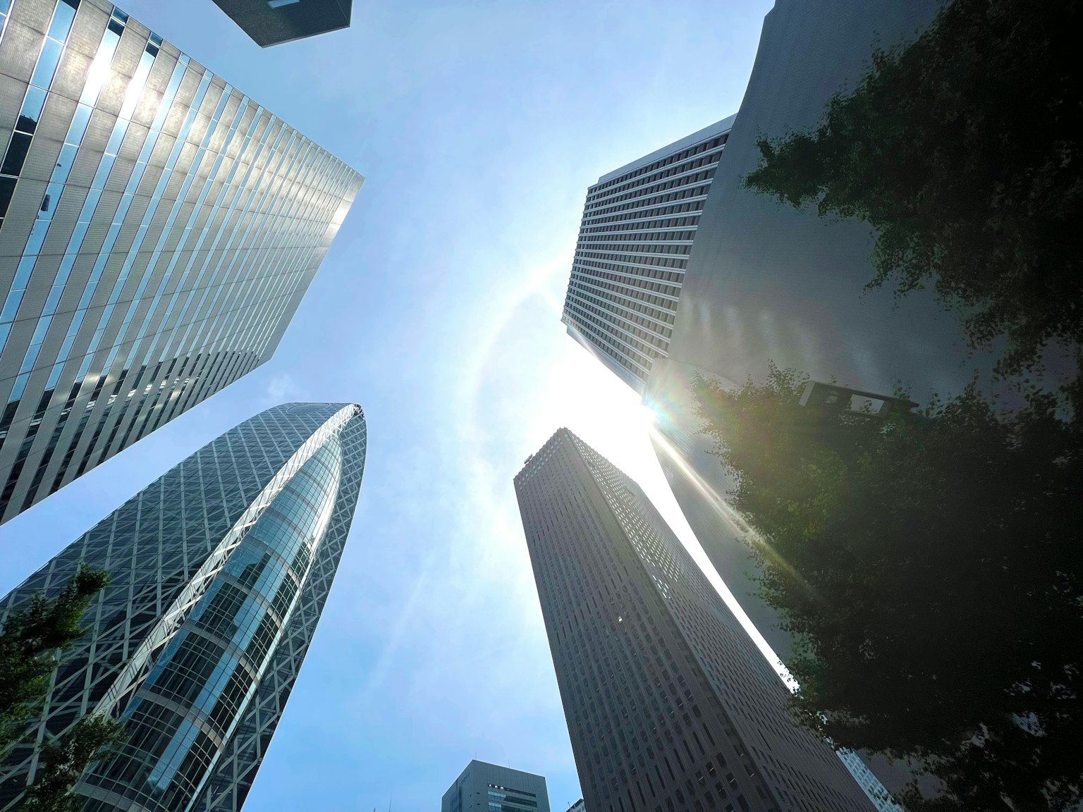 View looking up at skyscrapers with blue sky and sunlight