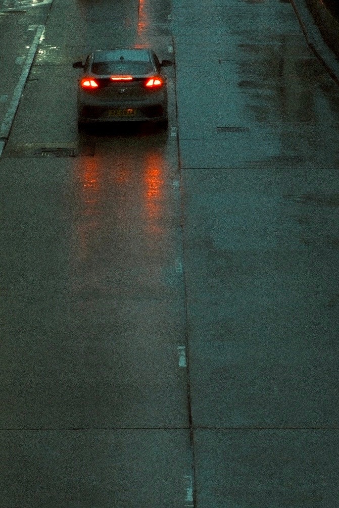 雨の路面を走る車のテールライトのある夜の街並み