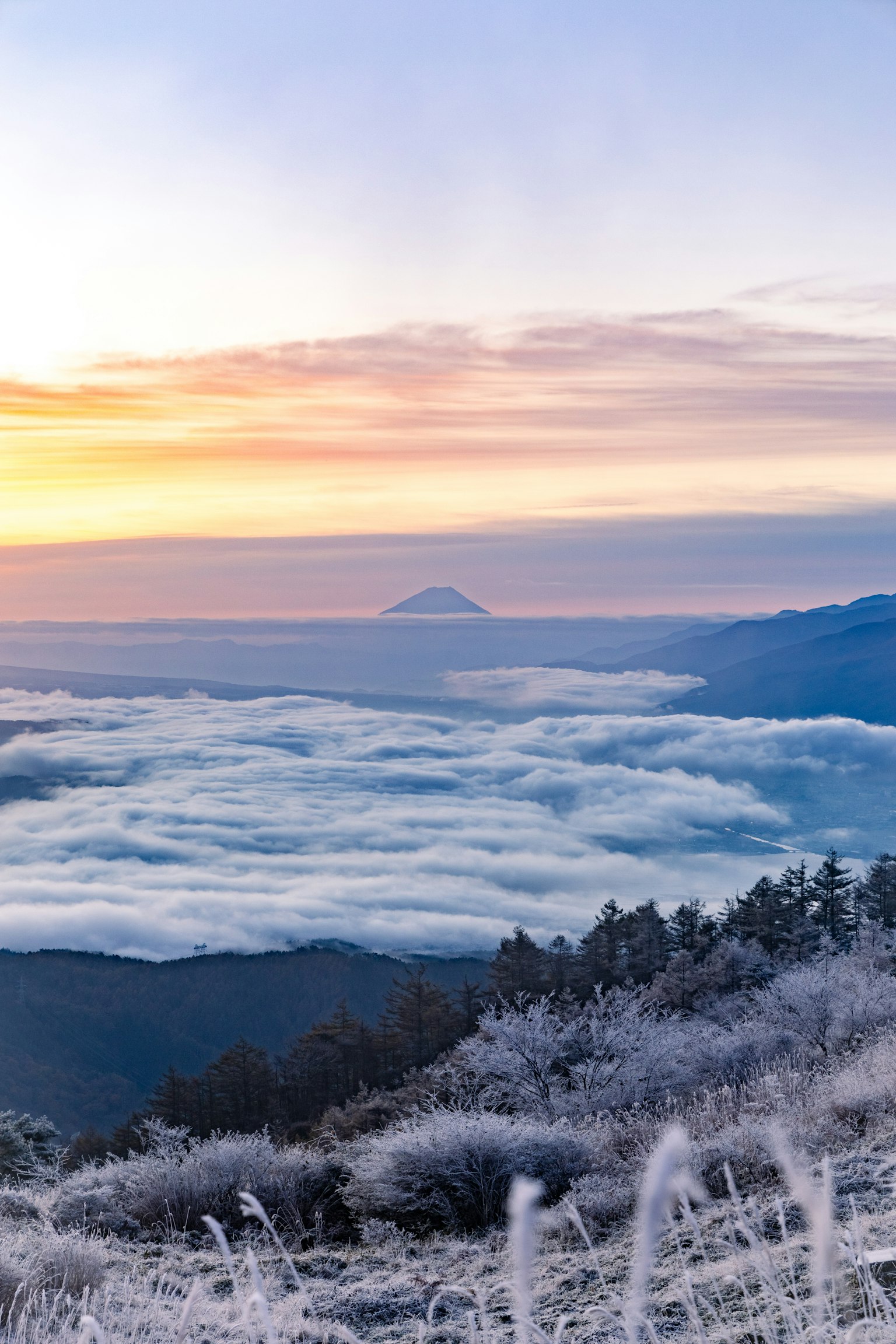 Winter morning landscape with fog covering mountains and sunrise