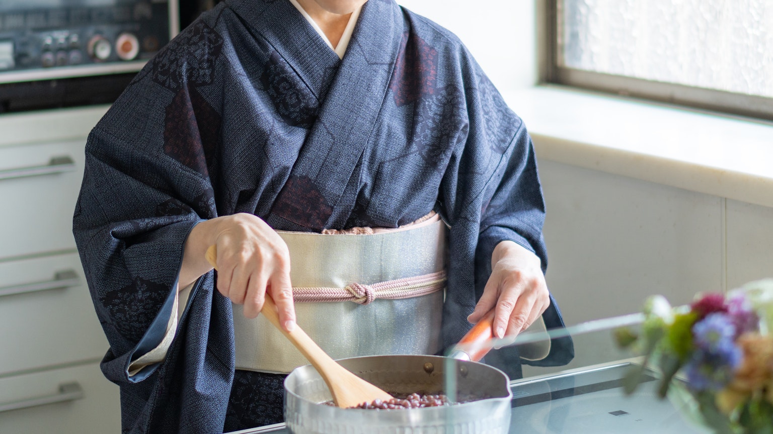 Mujer en kimono removiendo una olla en una cocina moderna