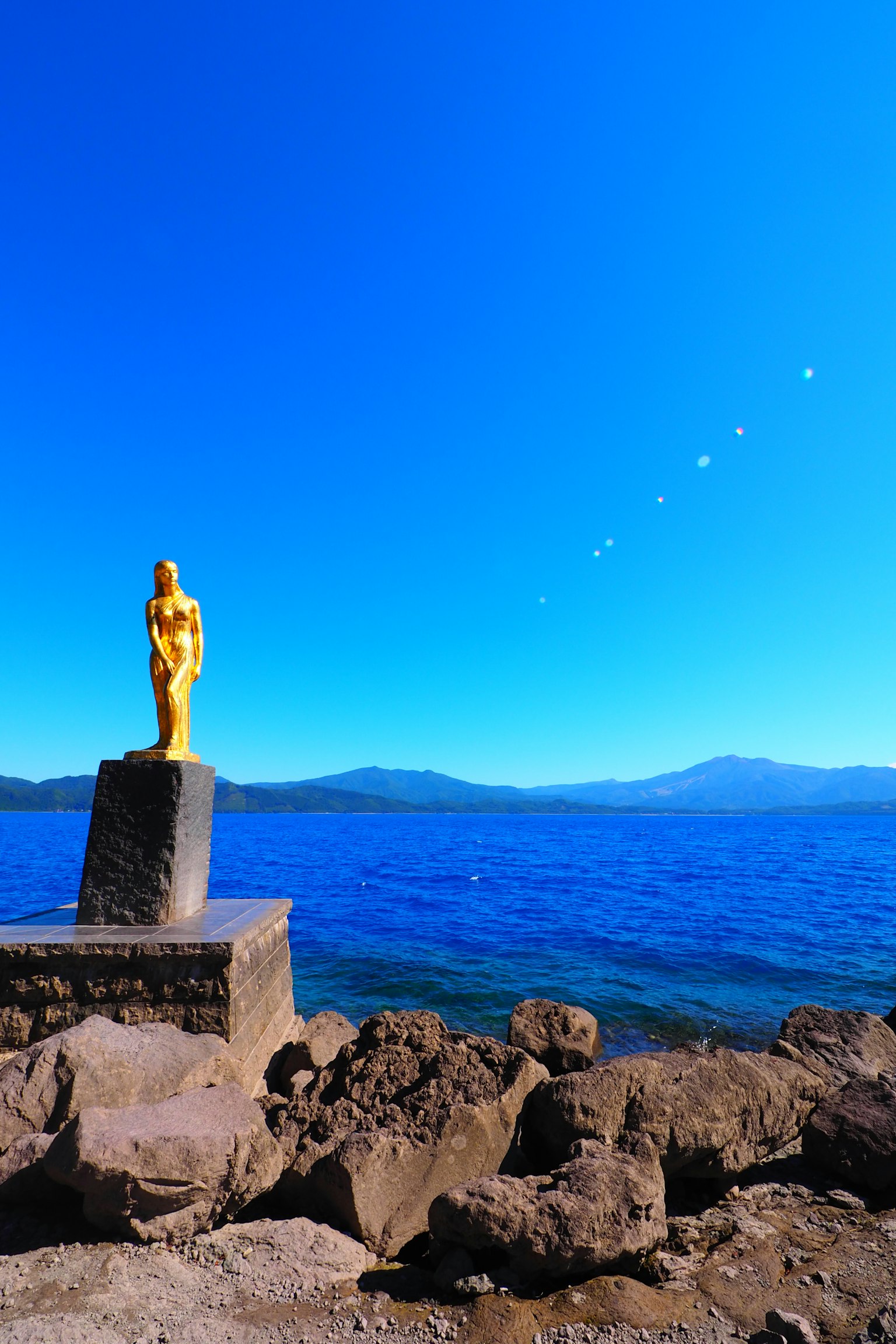 Estatua dorada de pie junto a la orilla del lago azul