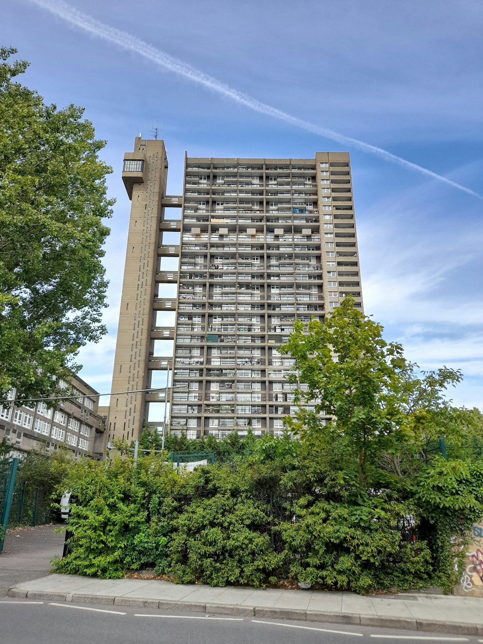 Un edificio alto de concreto distintivo rodeado de vegetación exuberante
