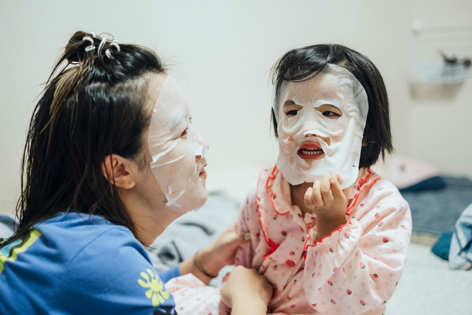 Madre e hija compartiendo un momento divertido con mascarillas en la cara